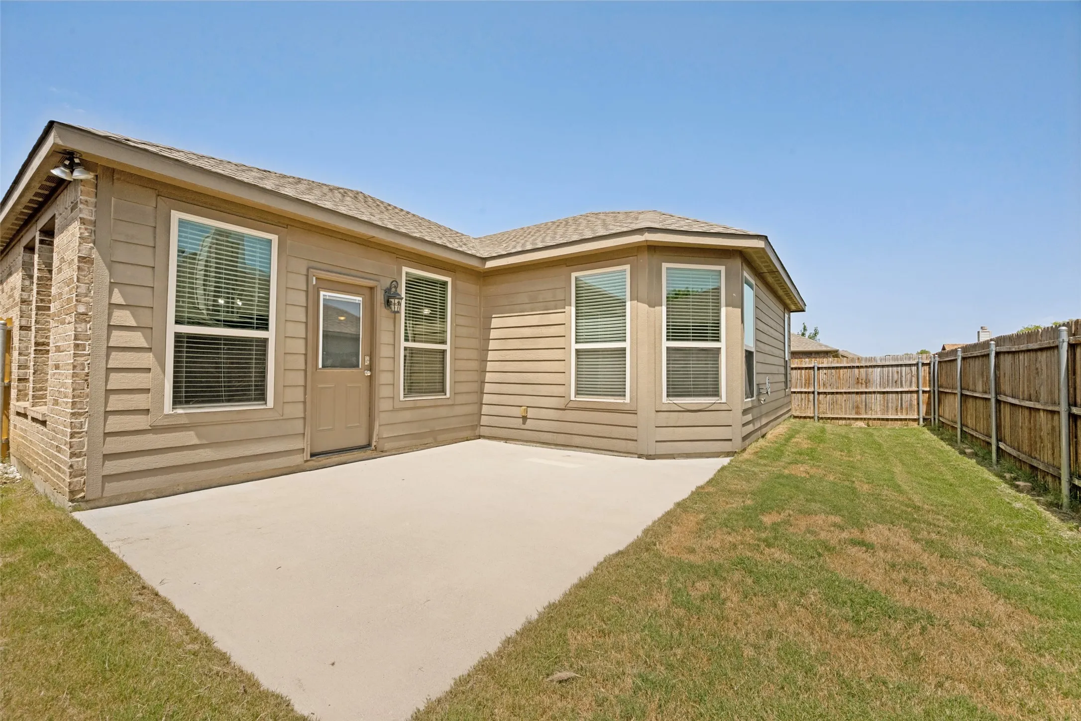 Spacious concrete patio featuring a perimeter privacy fence and a bay window
