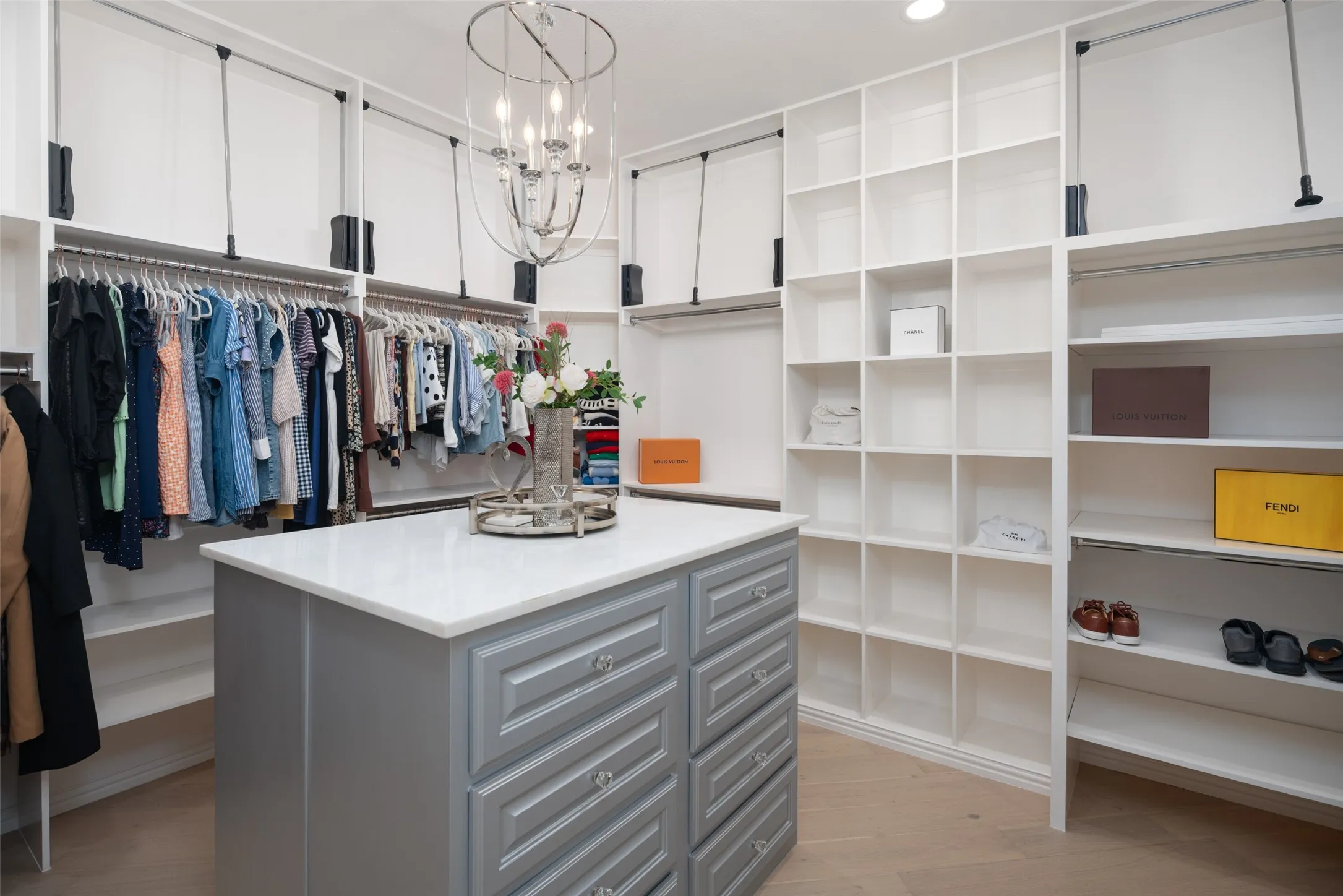 Custom-designed walk-in closet features extensive built-in cabinetry, center storage island, open shelving, hanging space, and boutique-style organization for an exceptional dressing experience.