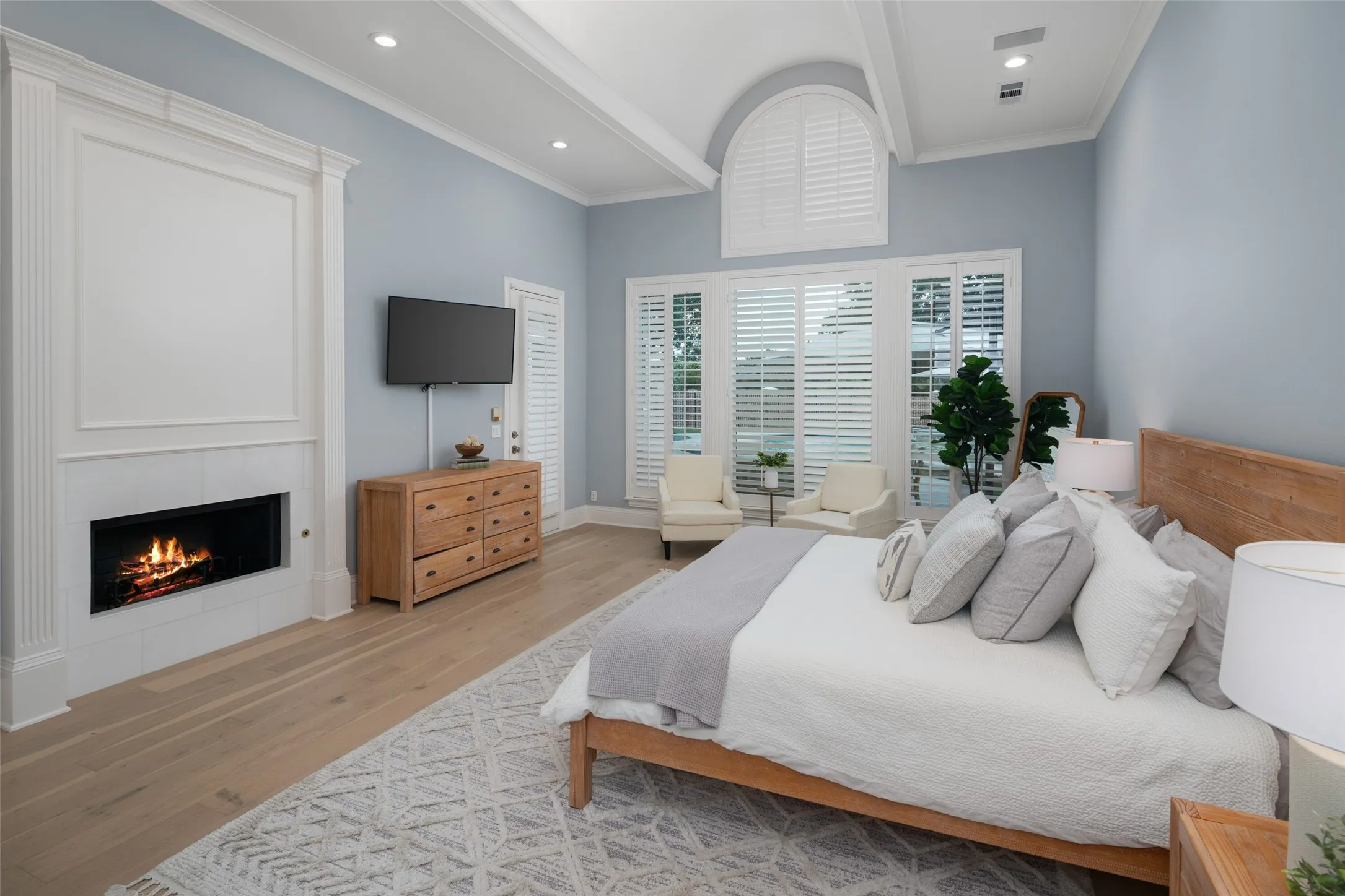Spacious owner's suite combines elegant architectural details, abundant natural light, fireplace, and peaceful backyard views, creating a luxurious retreat designed for comfort and relaxation.