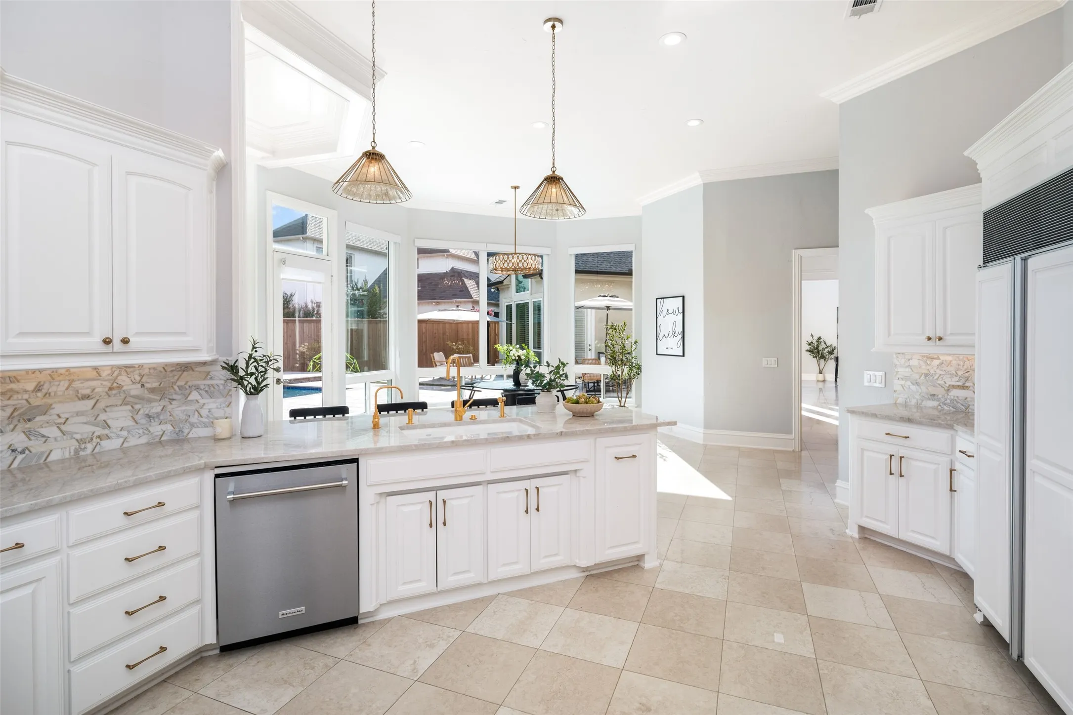A large center island with designer fixtures overlooks the breakfast room and backyard, while generous workspace, custom cabinetry, and premium finishes make this kitchen both beautiful and functional.