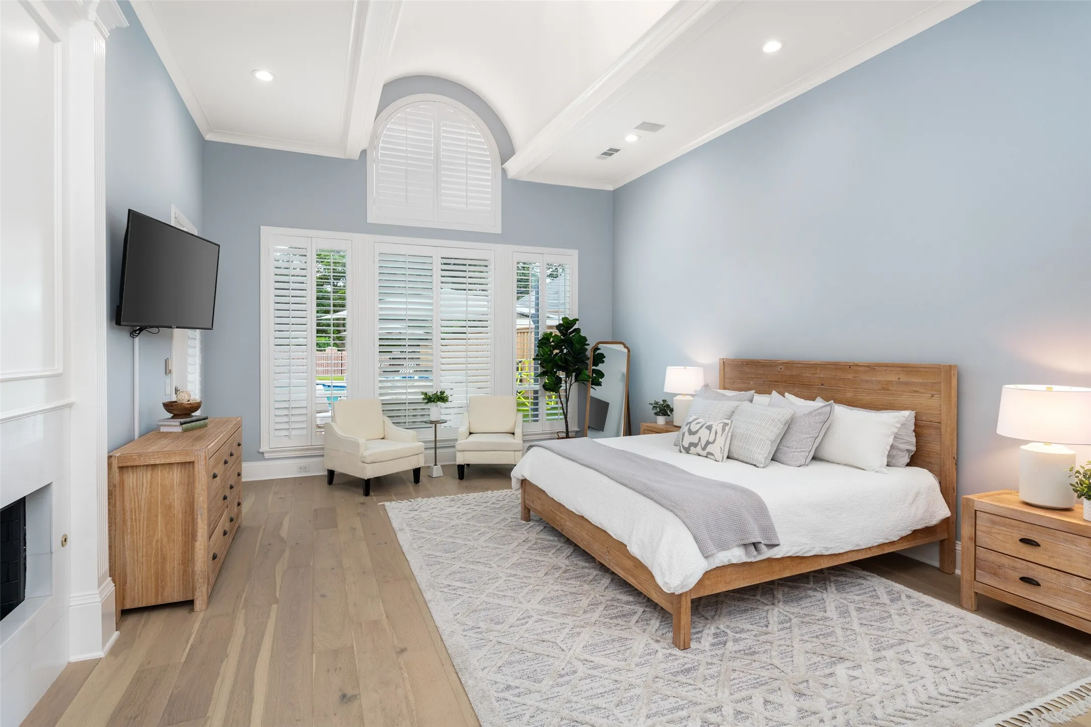 Private primary retreat with soaring beamed ceilings, fireplace, sitting area, expansive windows overlooking the backyard, and direct access to the luxurious spa-inspired bath and oversized custom walk-in closet.