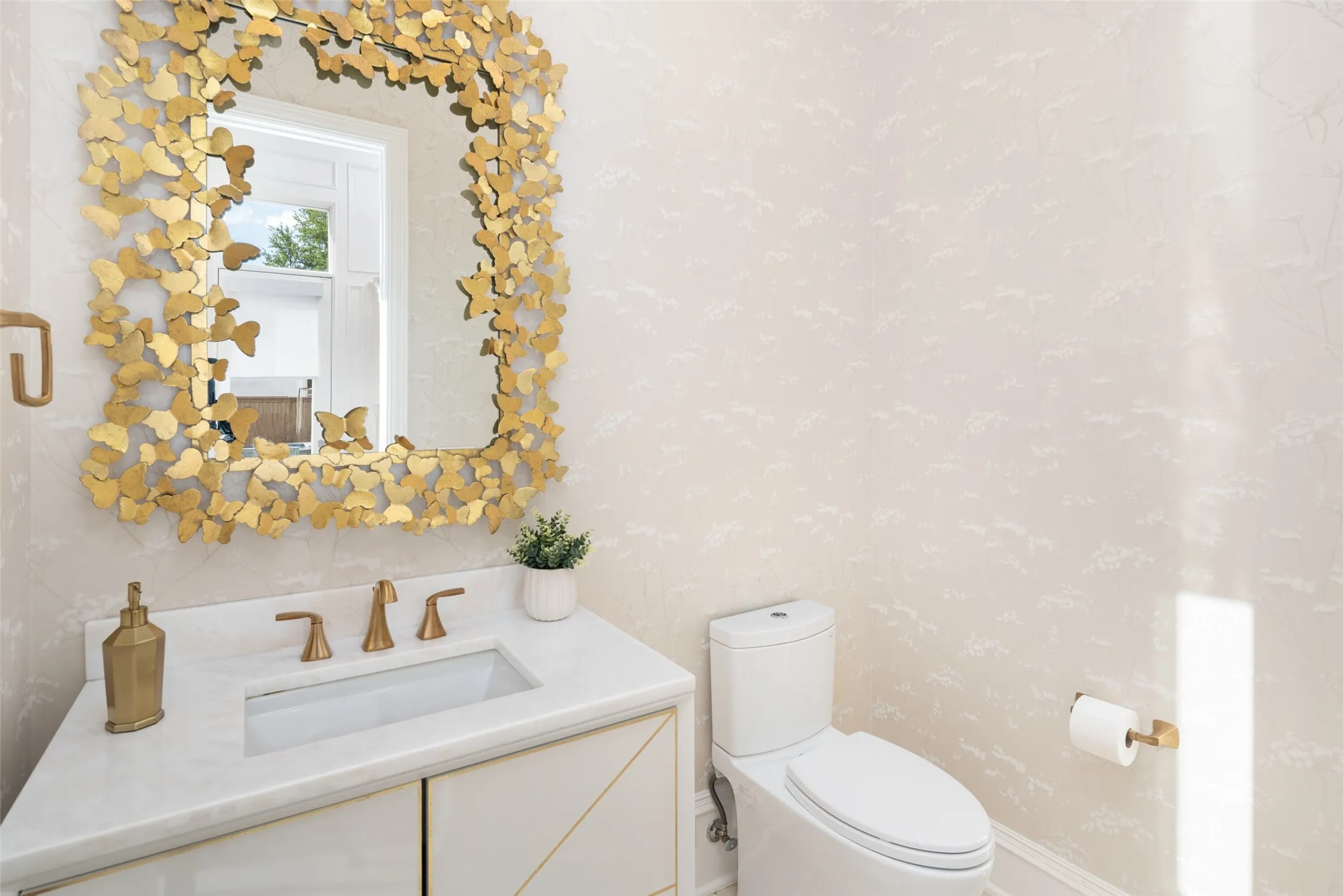 The beautifully appointed powder bath showcases designer wallpaper, custom cabinetry, quartz countertops, premium fixtures, and a striking statement mirror that creates an elegant first impression for guests.