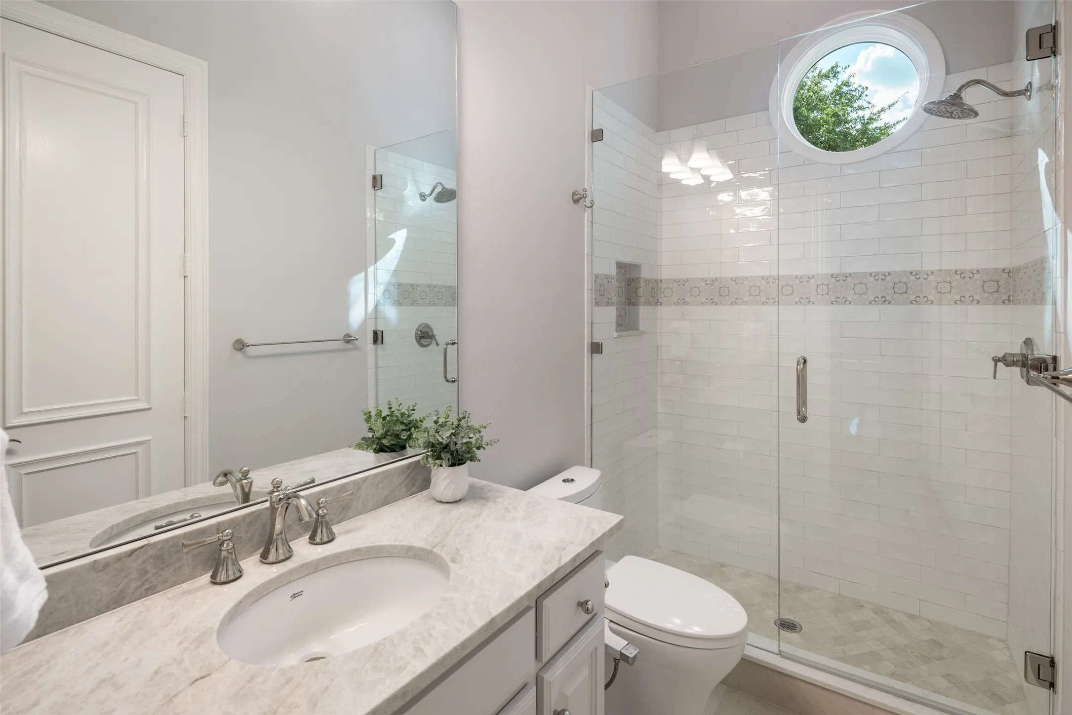The private ensuite features quartz countertops, marble flooring, a spacious glass-enclosed shower, and abundant natural light, providing guests with comfort and privacy on the first floor.