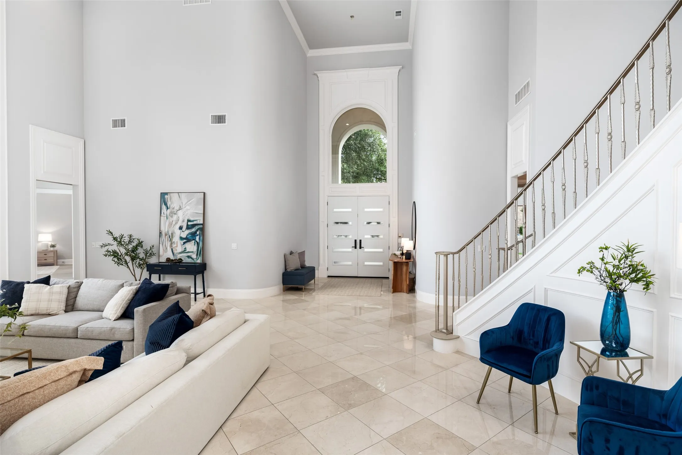 The dramatic two-story living room is filled with natural light from floor-to-ceiling windows overlooking the backyard. Marble floors, custom millwork, and soaring ceilings create an unforgettable gathering space.