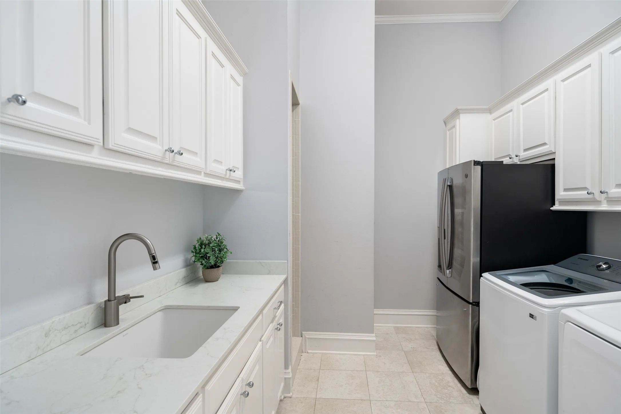 The oversized utility room features extensive cabinetry, quartz countertops, a utility sink, space for a full-size refrigerator, and abundant storage to simplify everyday household tasks.