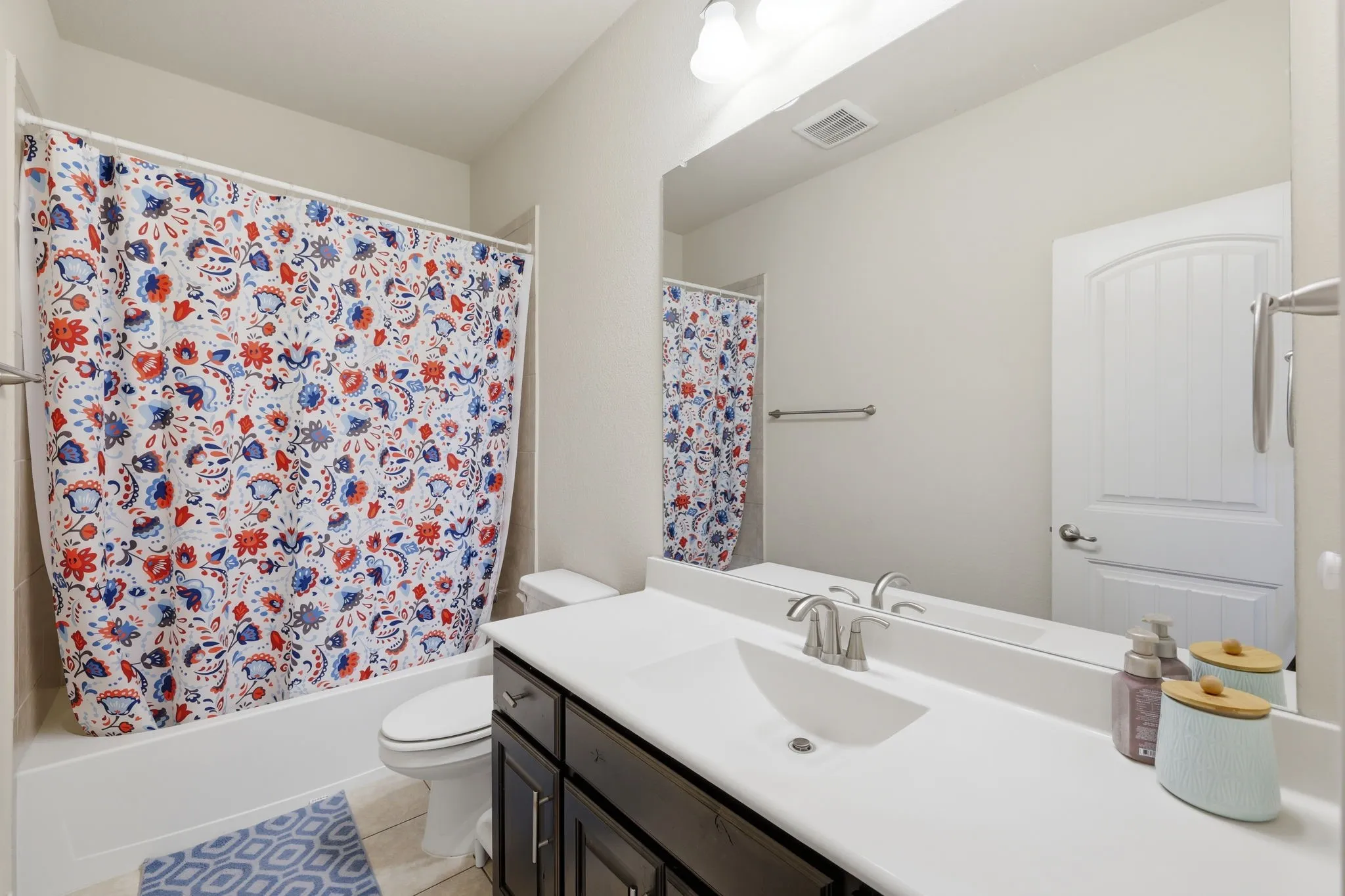 Bathroom featuring a dark wood-finish vanity with a white countertop, an integrated sink, brushed nickel faucet, and a large wall-mounted mirror