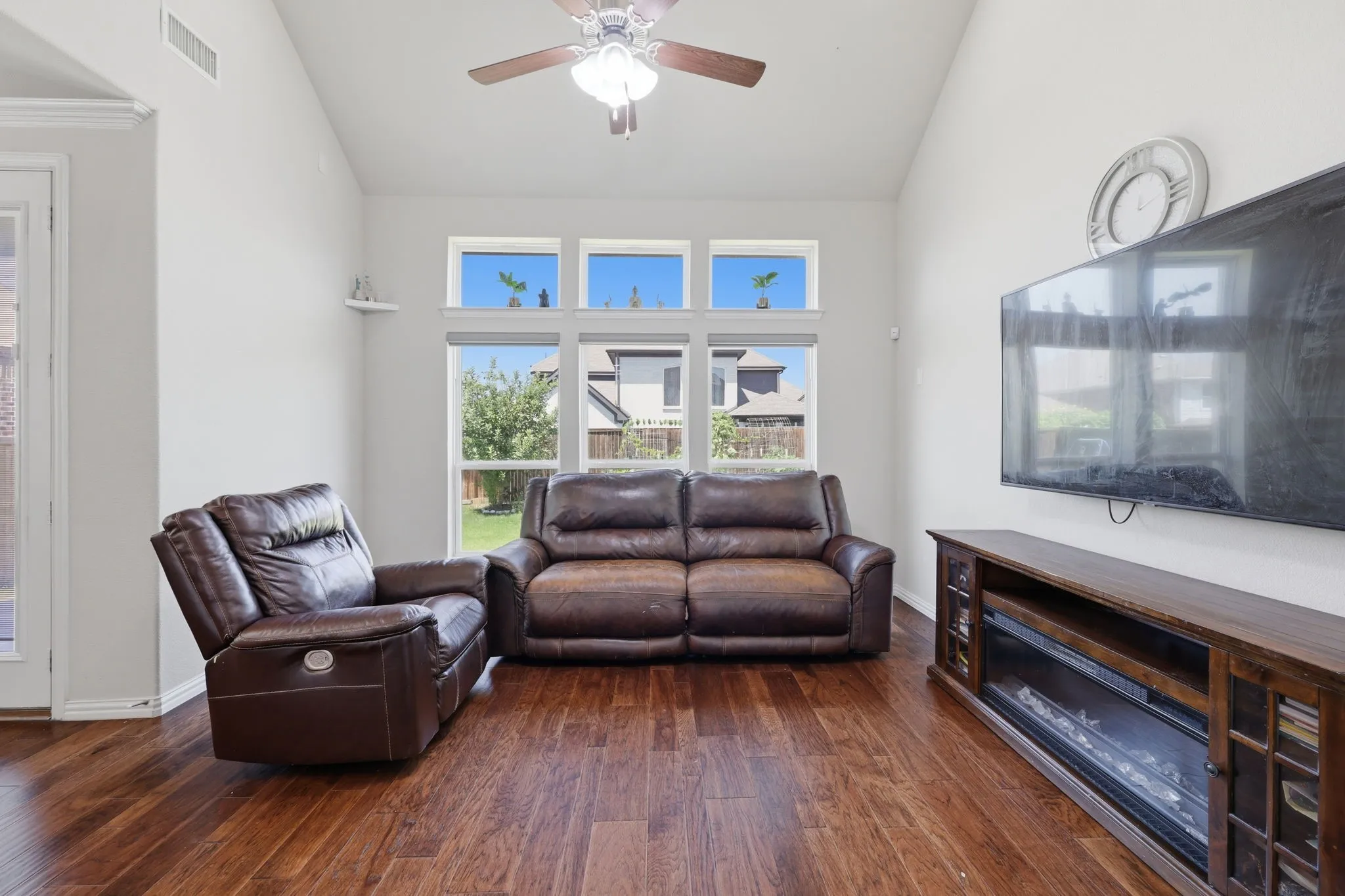 Spacious living area featuring high vaulted ceilings, wood-finish flooring, and multiple windows providing ample natural light