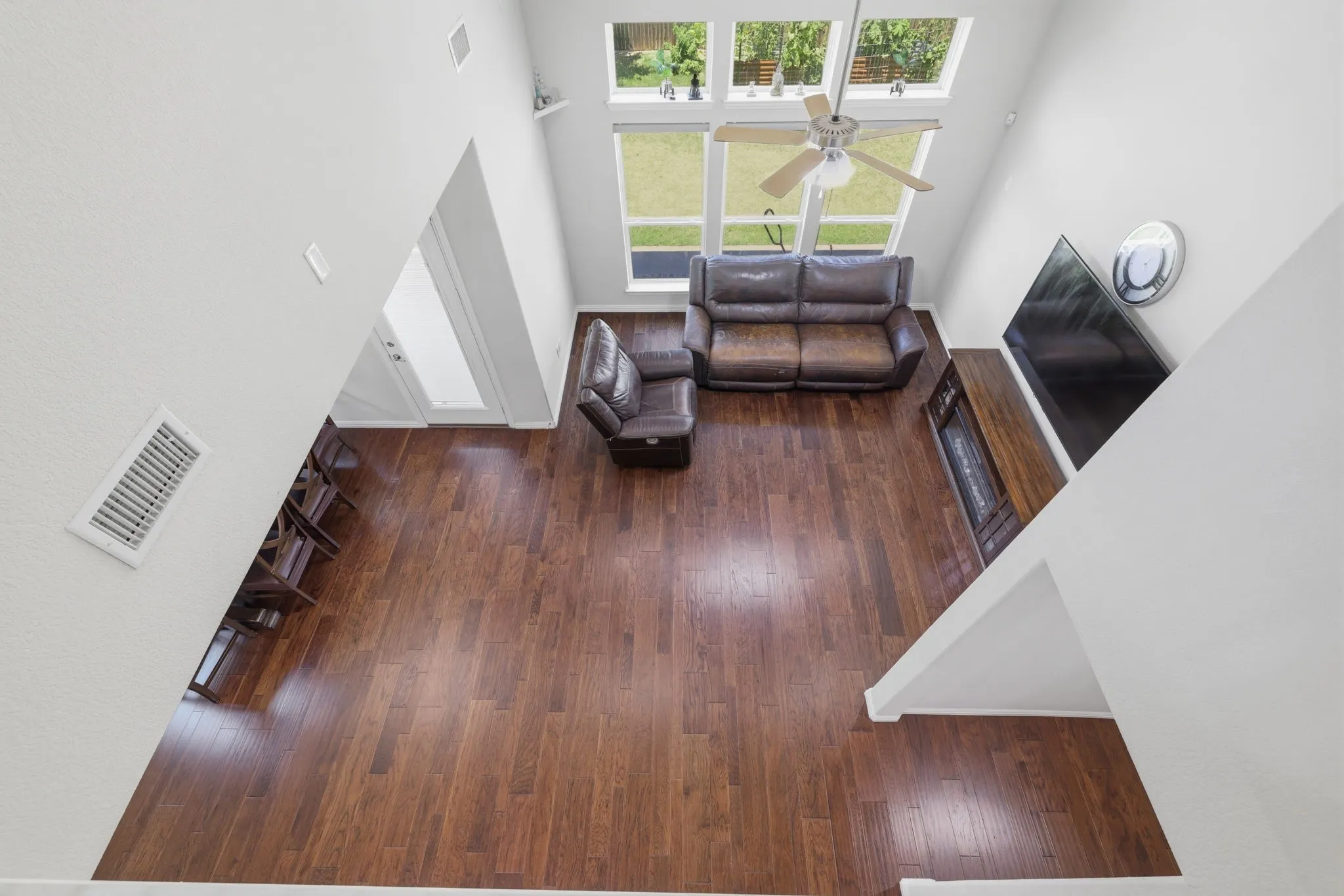 Soaring ceilings with upper windows and a ceiling fan highlight this living area