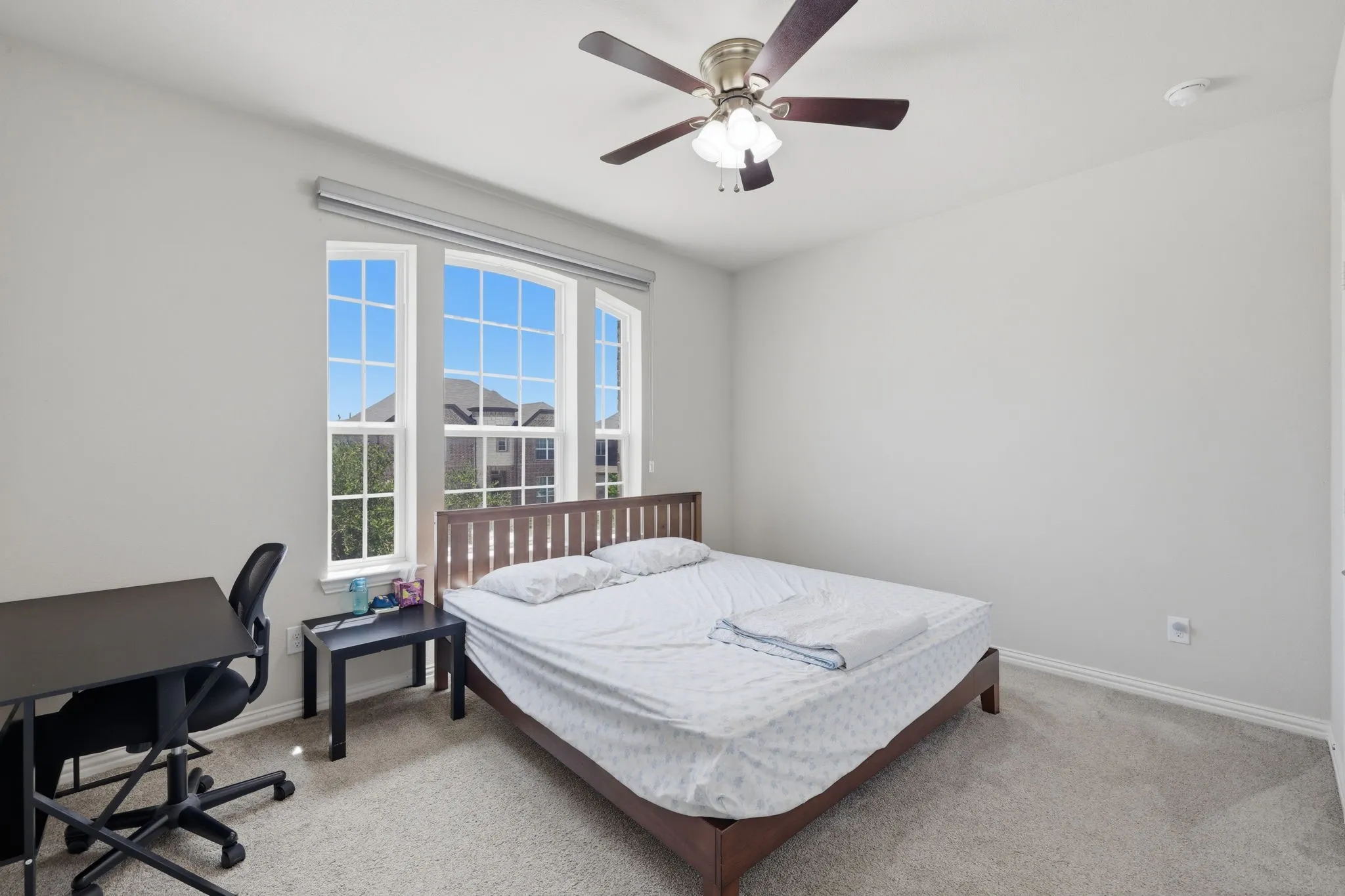 Room featuring large arched windows with grid patterns, light gray walls, and carpet flooring