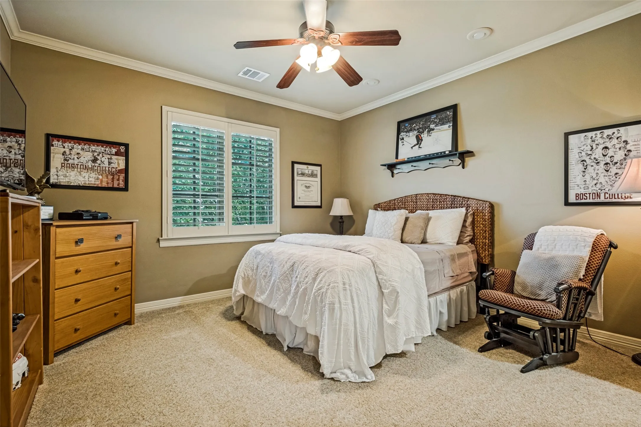 Recessed lighting and a ceiling fan fixture illuminate this carpeted room, featuring a window with white louvered shutters