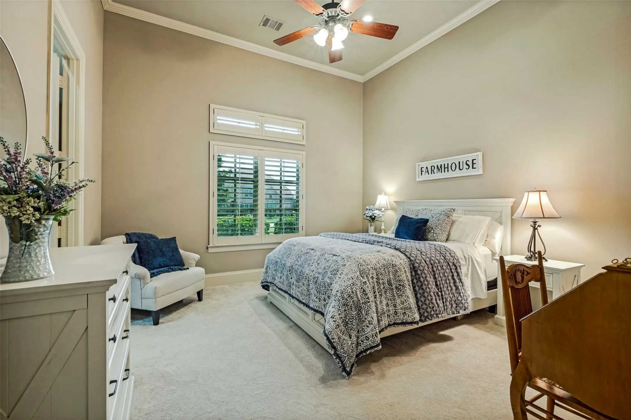 Downstairs bedroom with tray ceiling, fan, crown molding, and plantation shutters.