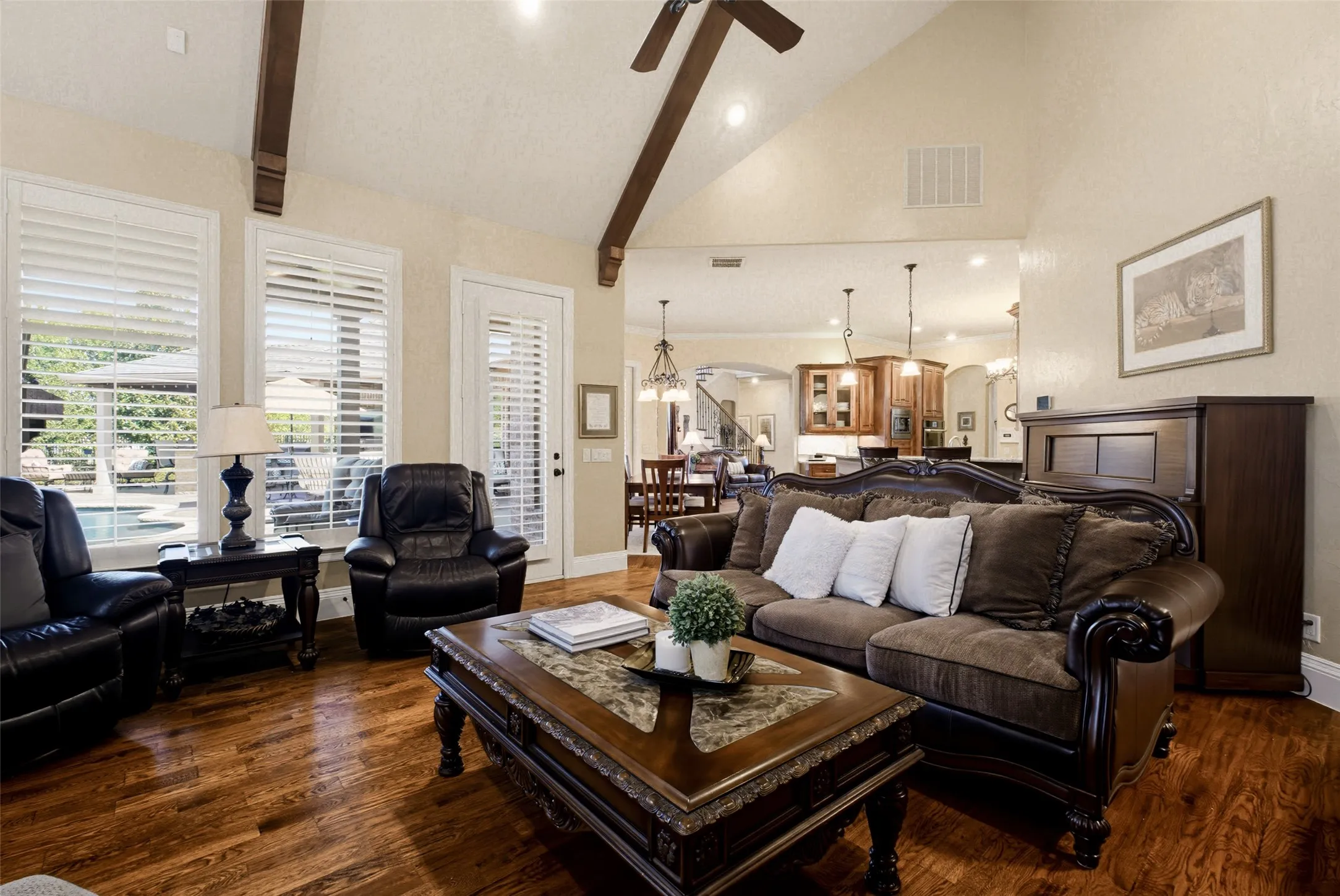 Vaulted ceiling with exposed wood beams, wood-finish flooring, plantation shutters, and recessed lighting