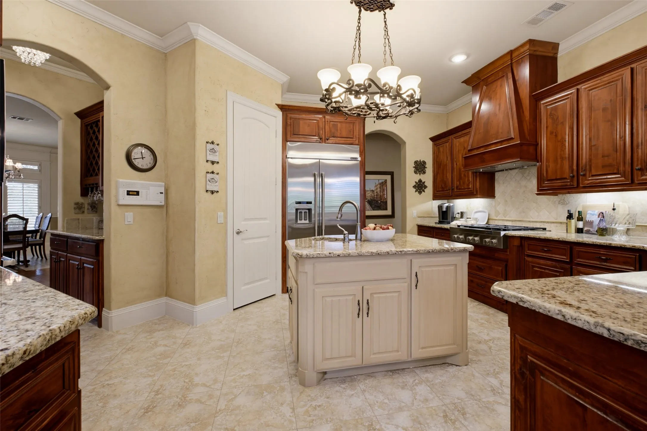 Kitchen featuring granite countertops, wood cabinetry, stainless steel appliances, a center island, and tile flooring