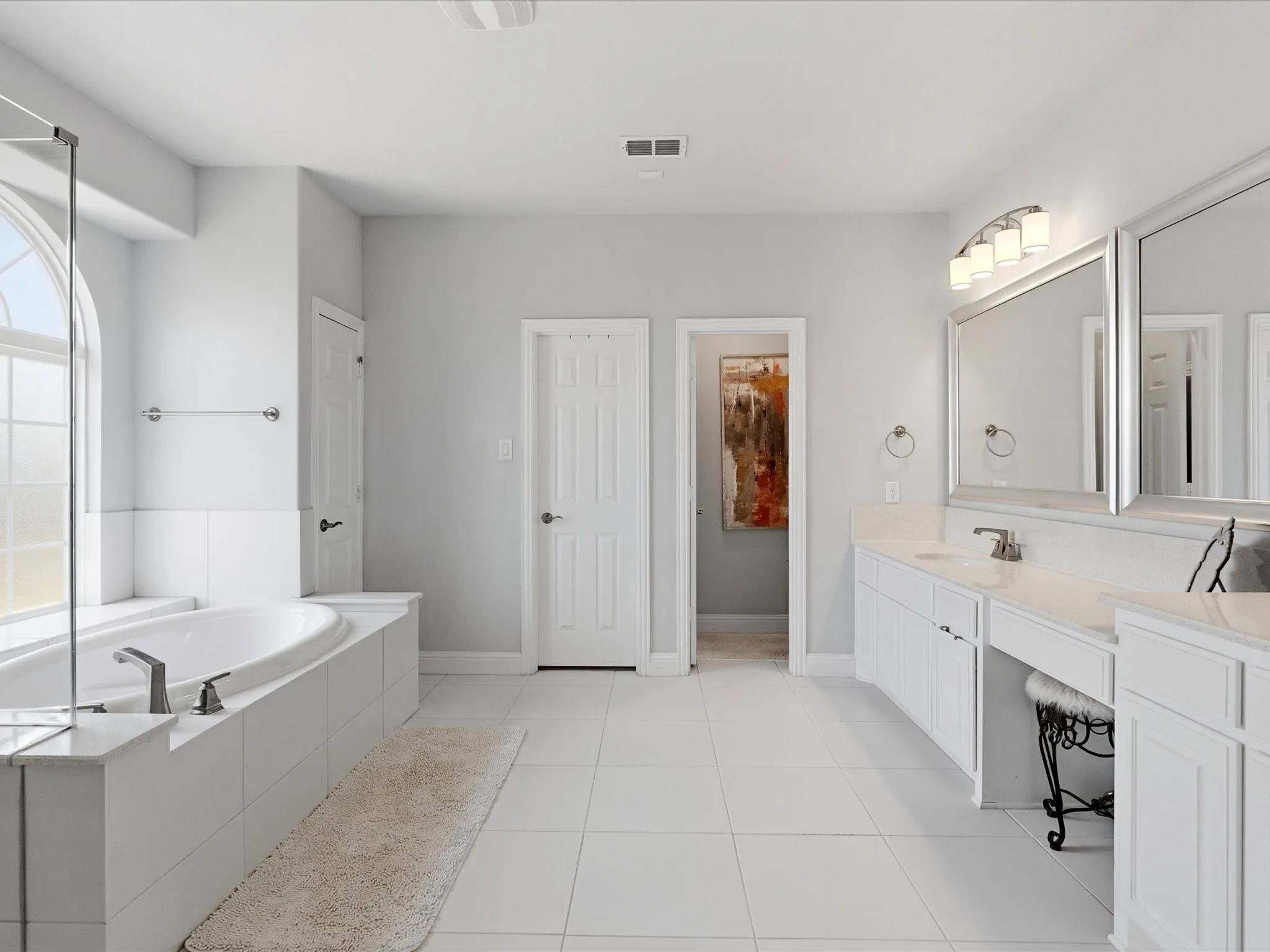 Sparkling white primary bath features large his and hers closet with convenient laundry room access