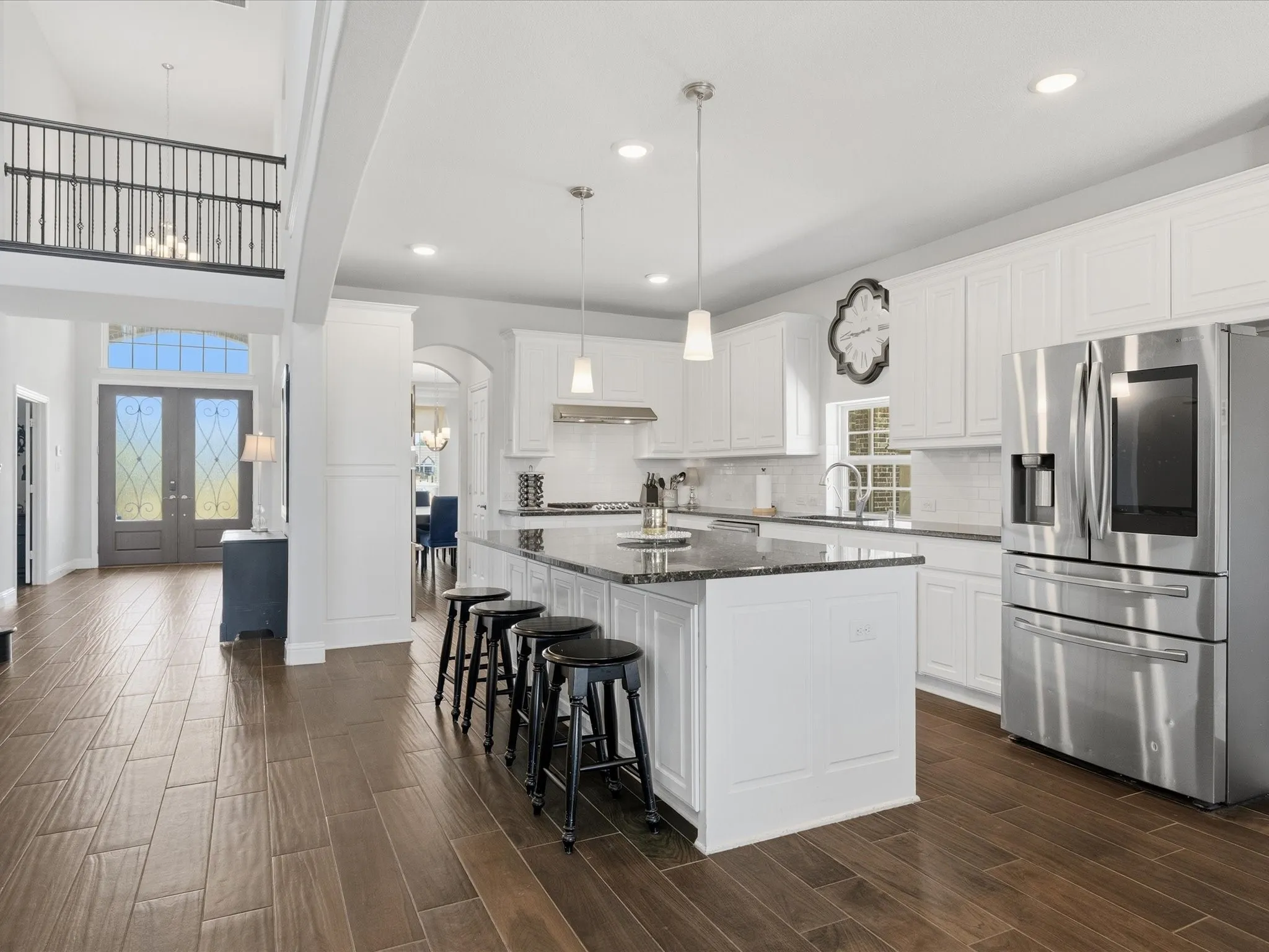 Large bright white kitchen features granite surfaces and stainless steel appliances