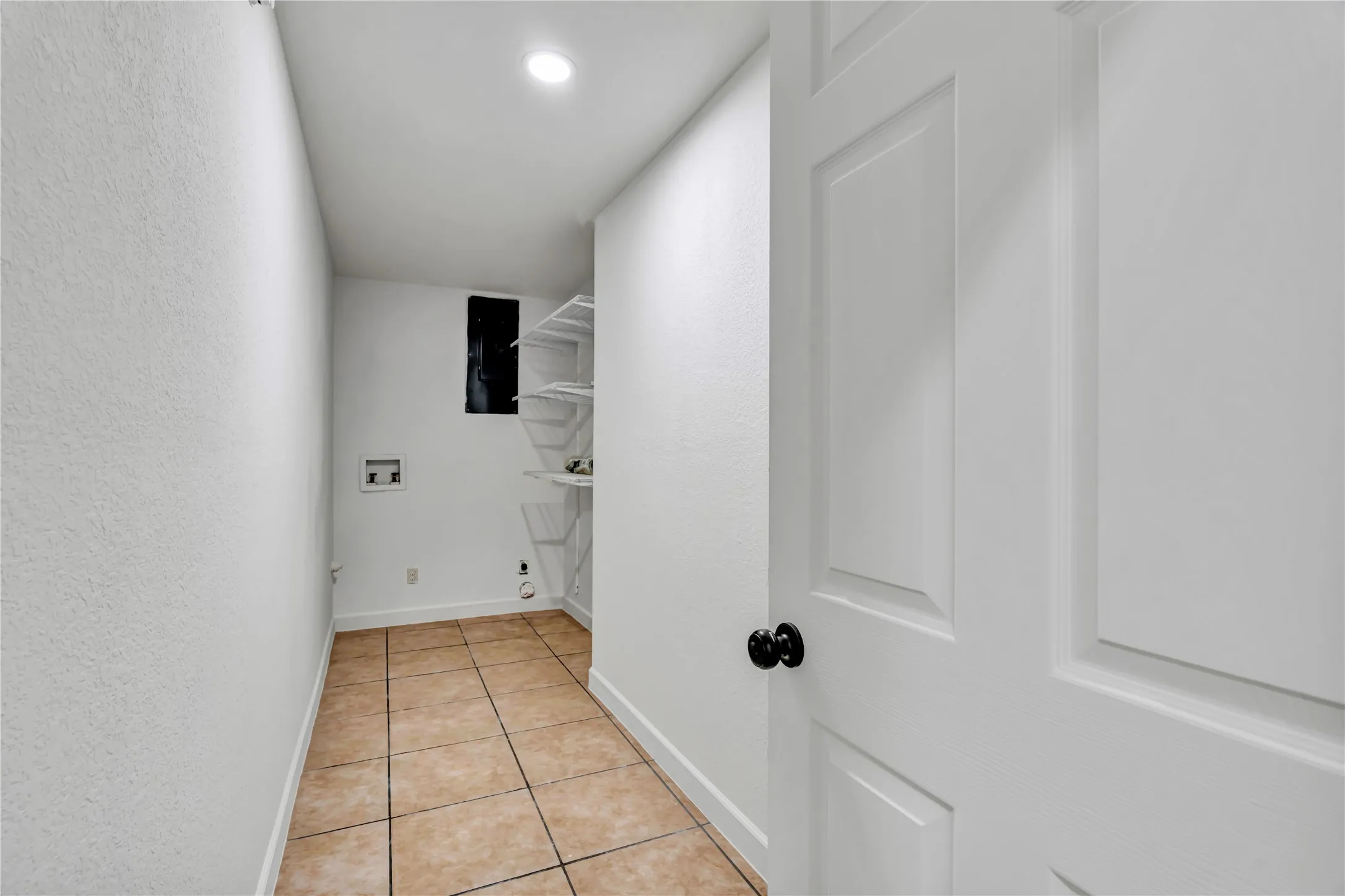 Laundry area with ceramic tile flooring, textured white walls, recessed ceiling lighting, and wire shelving