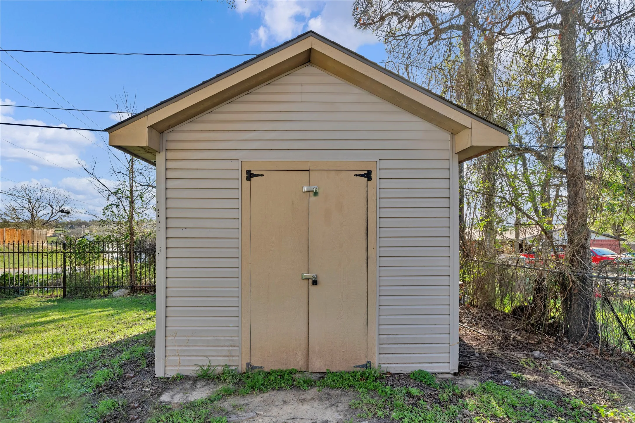 Gable-roof storage shed featuring horizontal siding, double doors with exterior latches, and a shallow pitched roofline