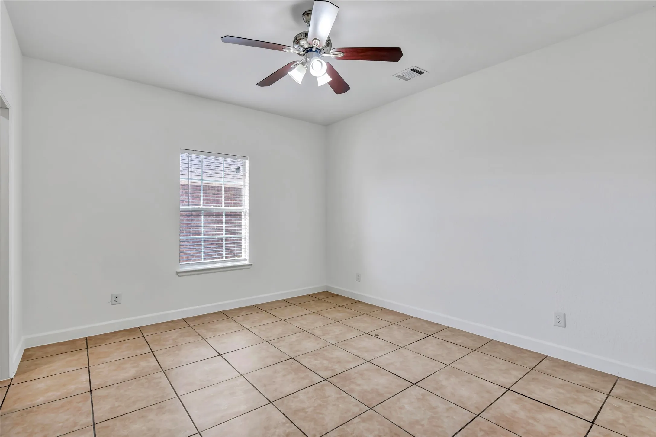 Neutral-toned tile flooring extends throughout this room, complemented by white painted walls and white baseboards