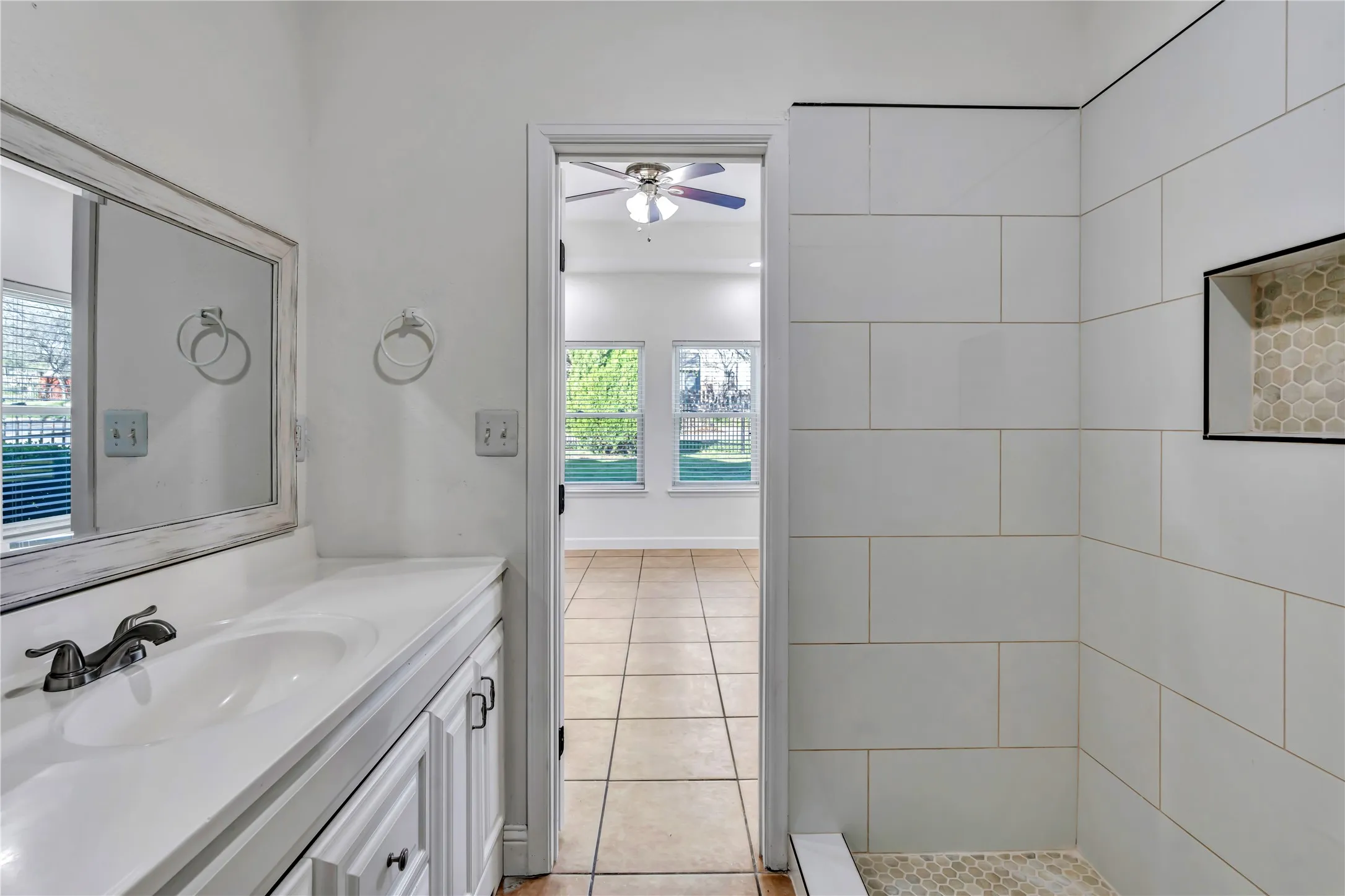 White vanity with integrated sink and distressed white-framed mirror