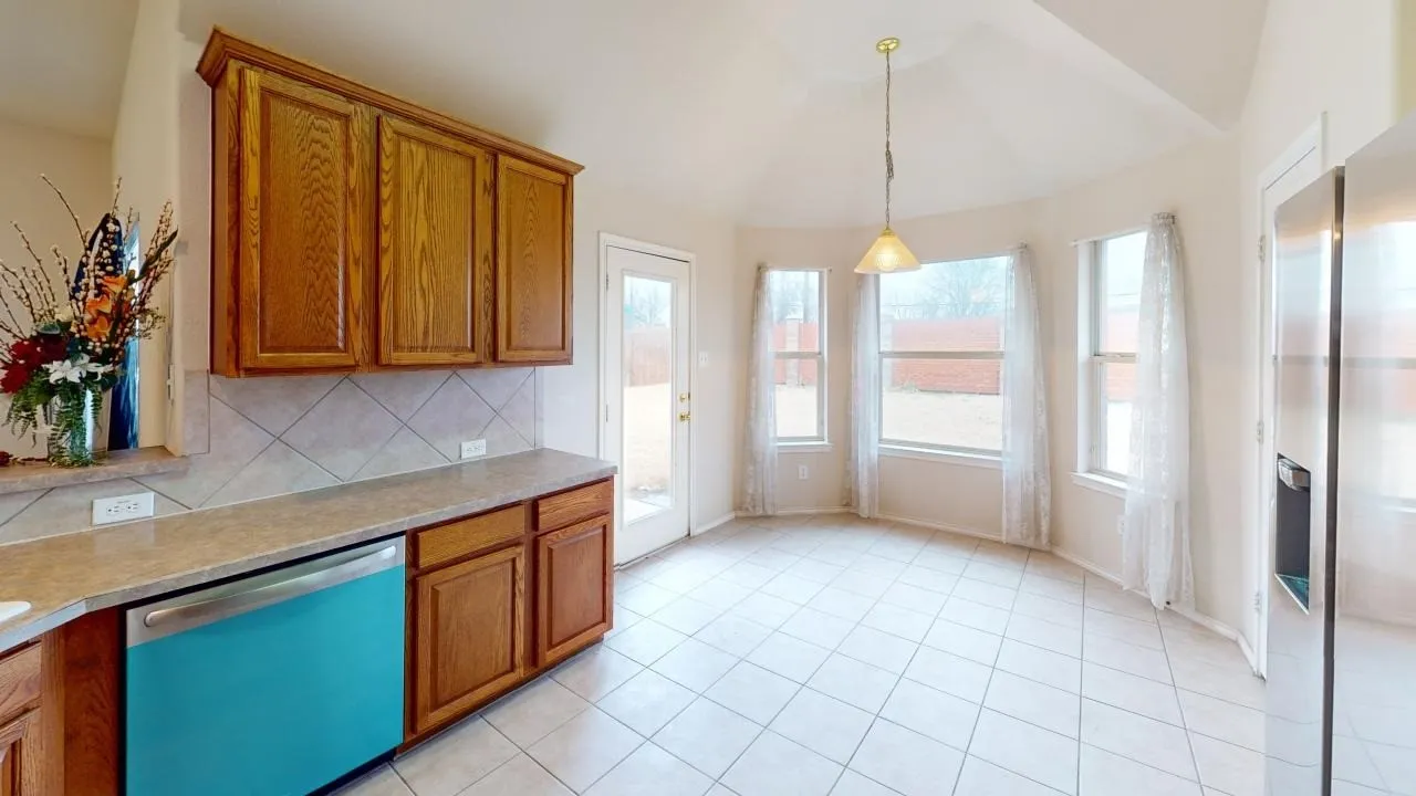 Kitchen area featuring wood cabinetry, a tiled backsplash, and light-toned countertops