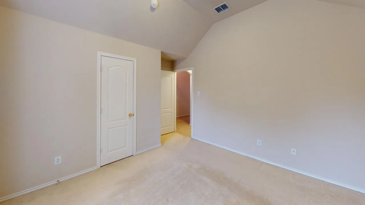 Room featuring vaulted ceilings, neutral wall tones, and plush carpeting