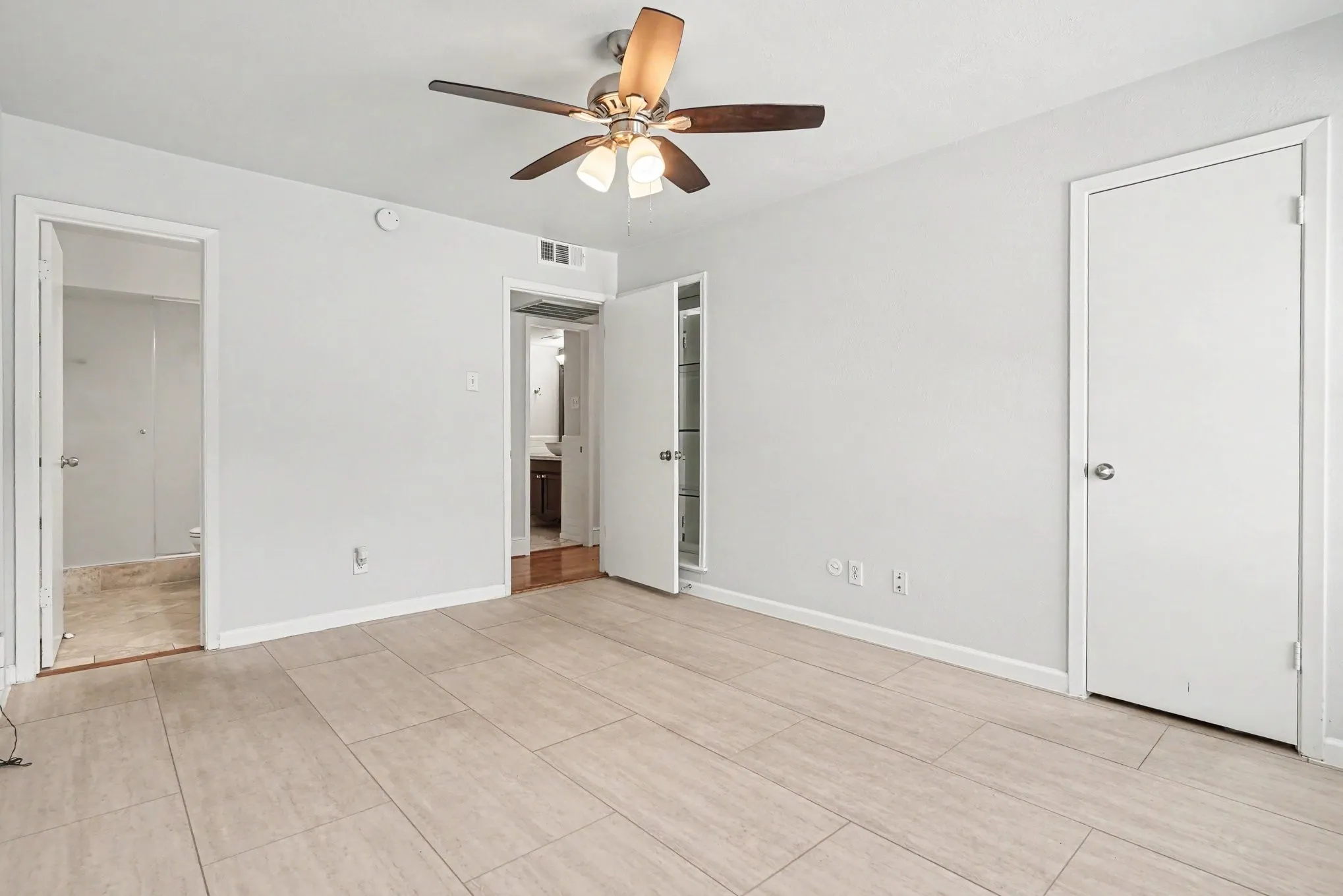 Another primary bedroom view with doors open to the bath at the left and the hall at the center.  The walk-in closet door is closed.