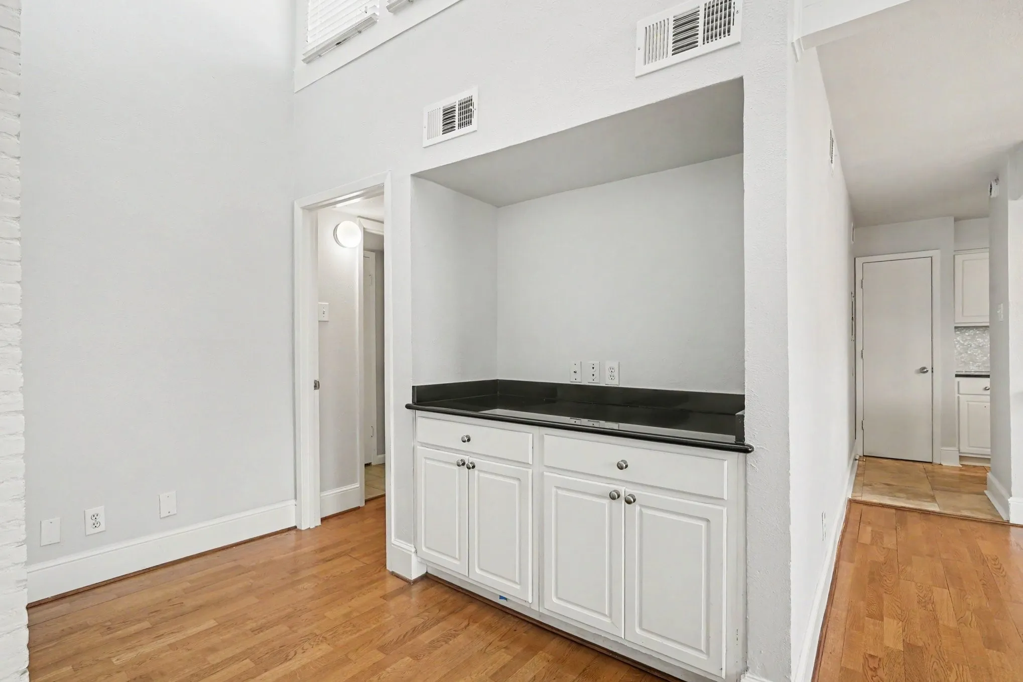 A direct view of the dry bar with extra storage and dark granite counter in the living room.