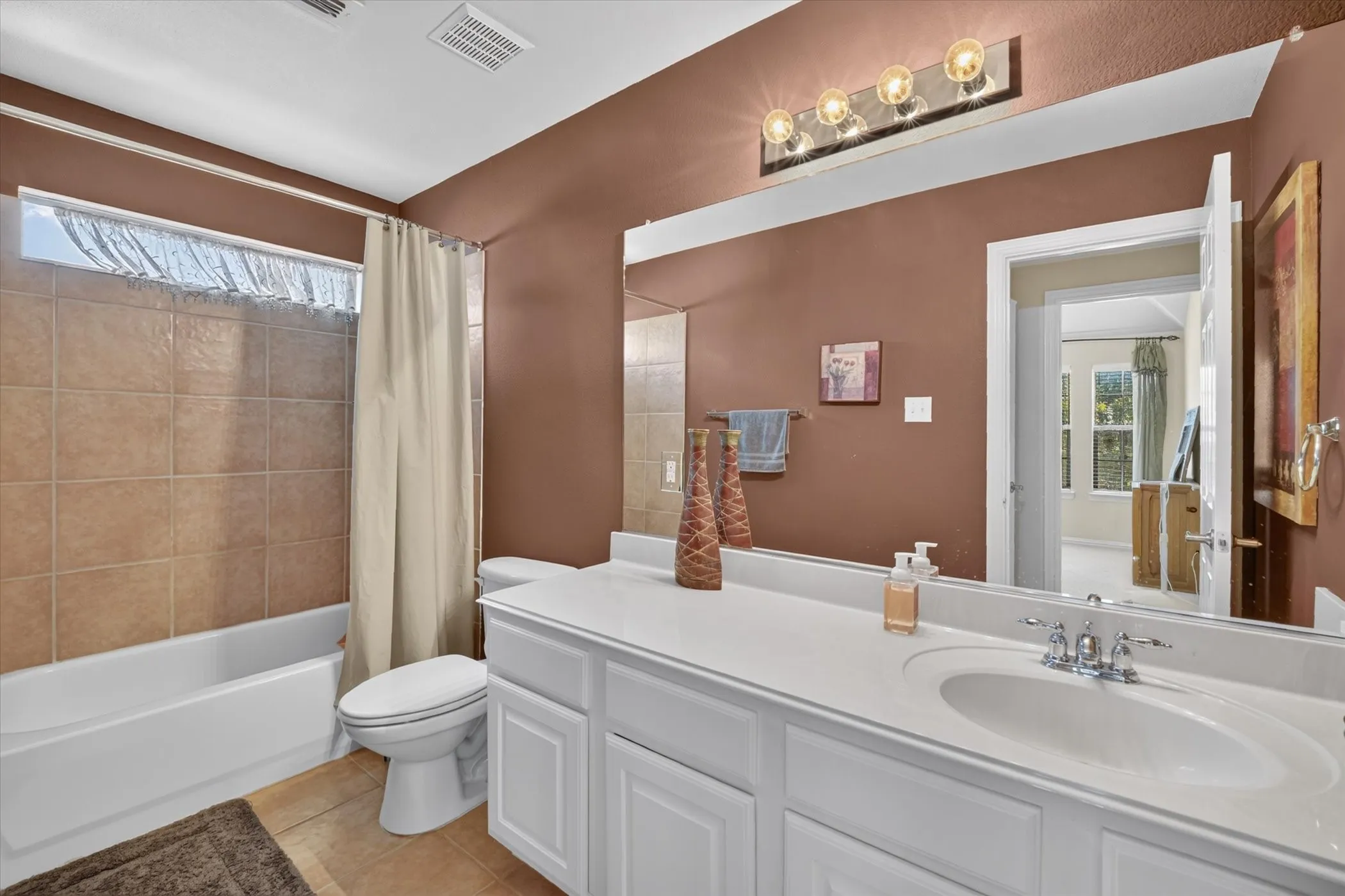 Full bathroom featuring a white vanity with integrated sink, a large mirror, and a chrome light fixture with multiple bulbs