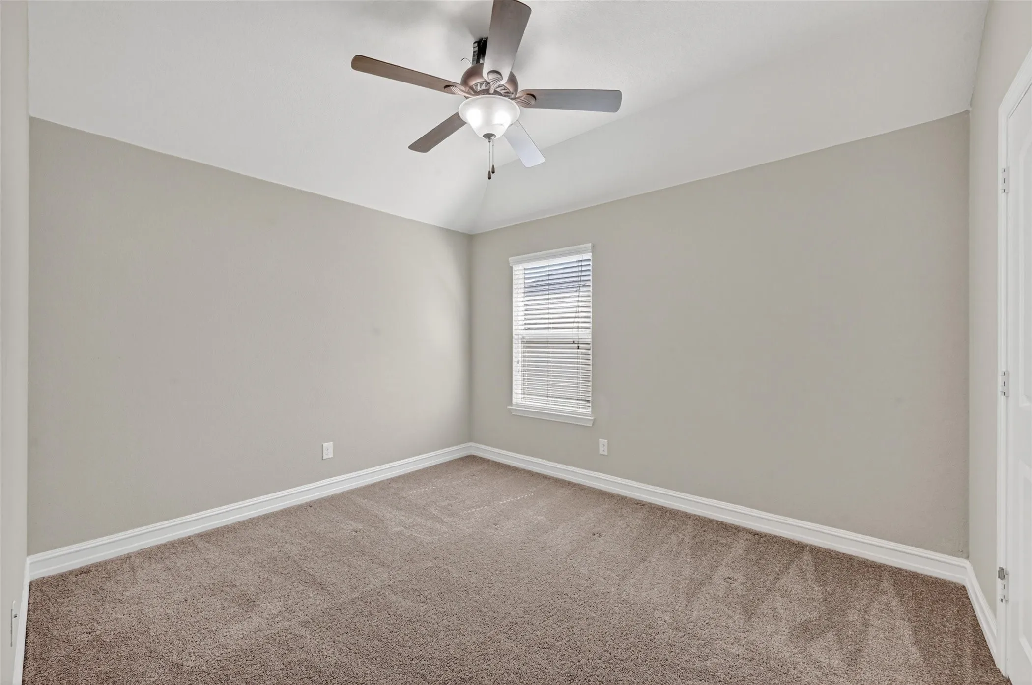Carpeted room featuring a ceiling fan with light fixture, window with blinds, and white trim