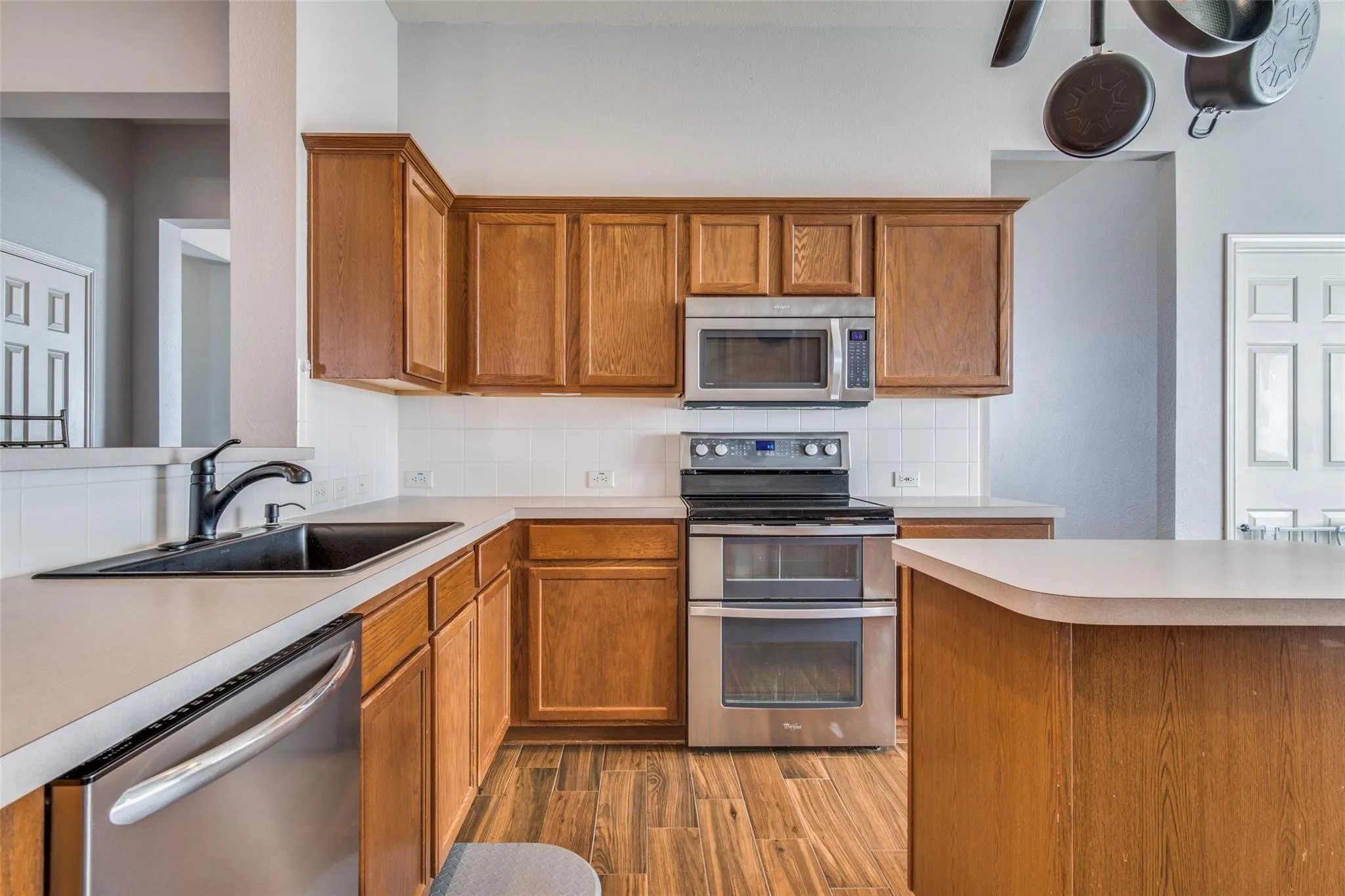 Kitchen featuring wood-finish cabinetry, stainless steel appliances, a double oven range, and a black basin sink with a matte black faucet