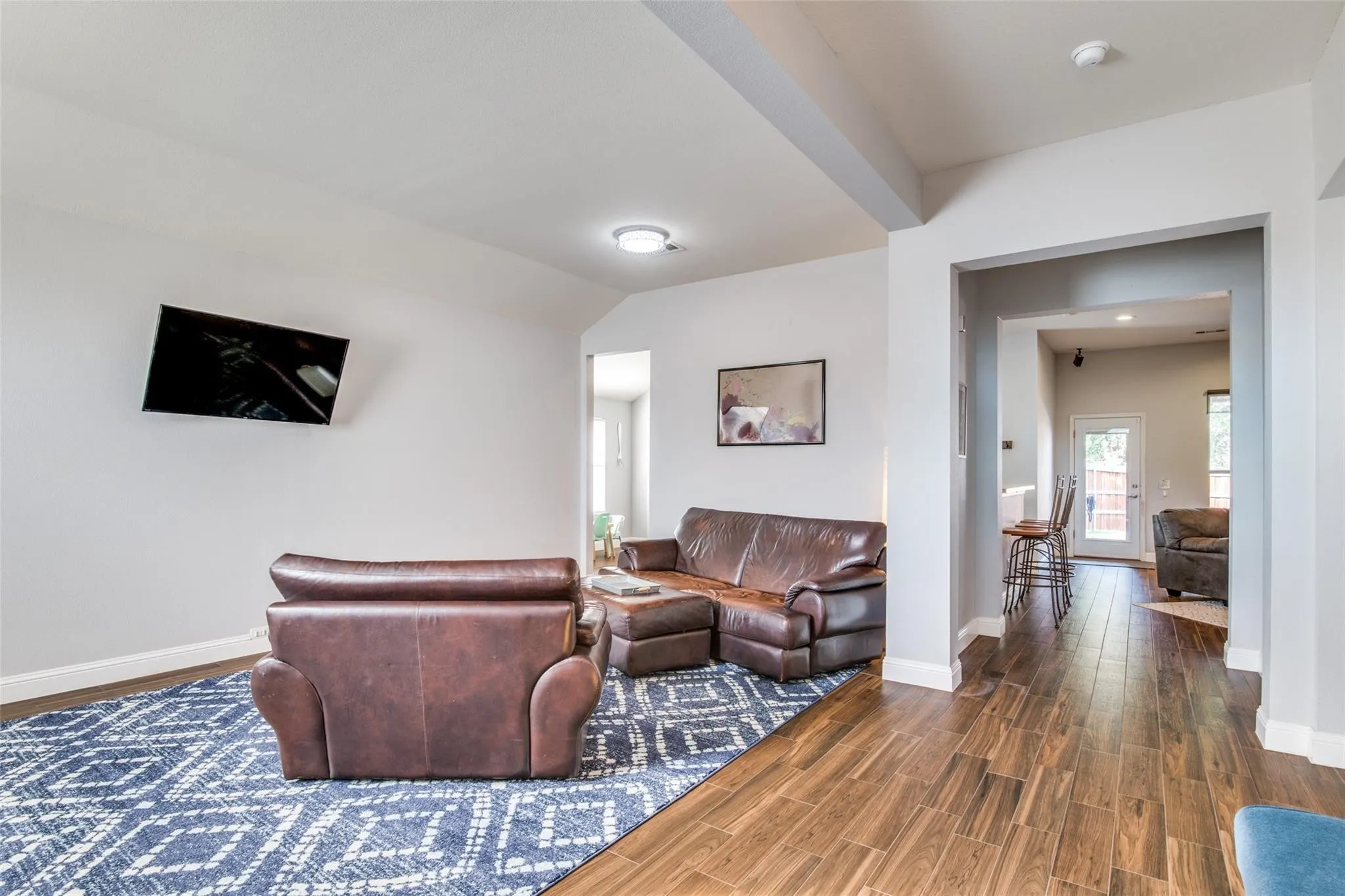 Spacious living area featuring wood-finish flooring, light grey walls, and an open archway
