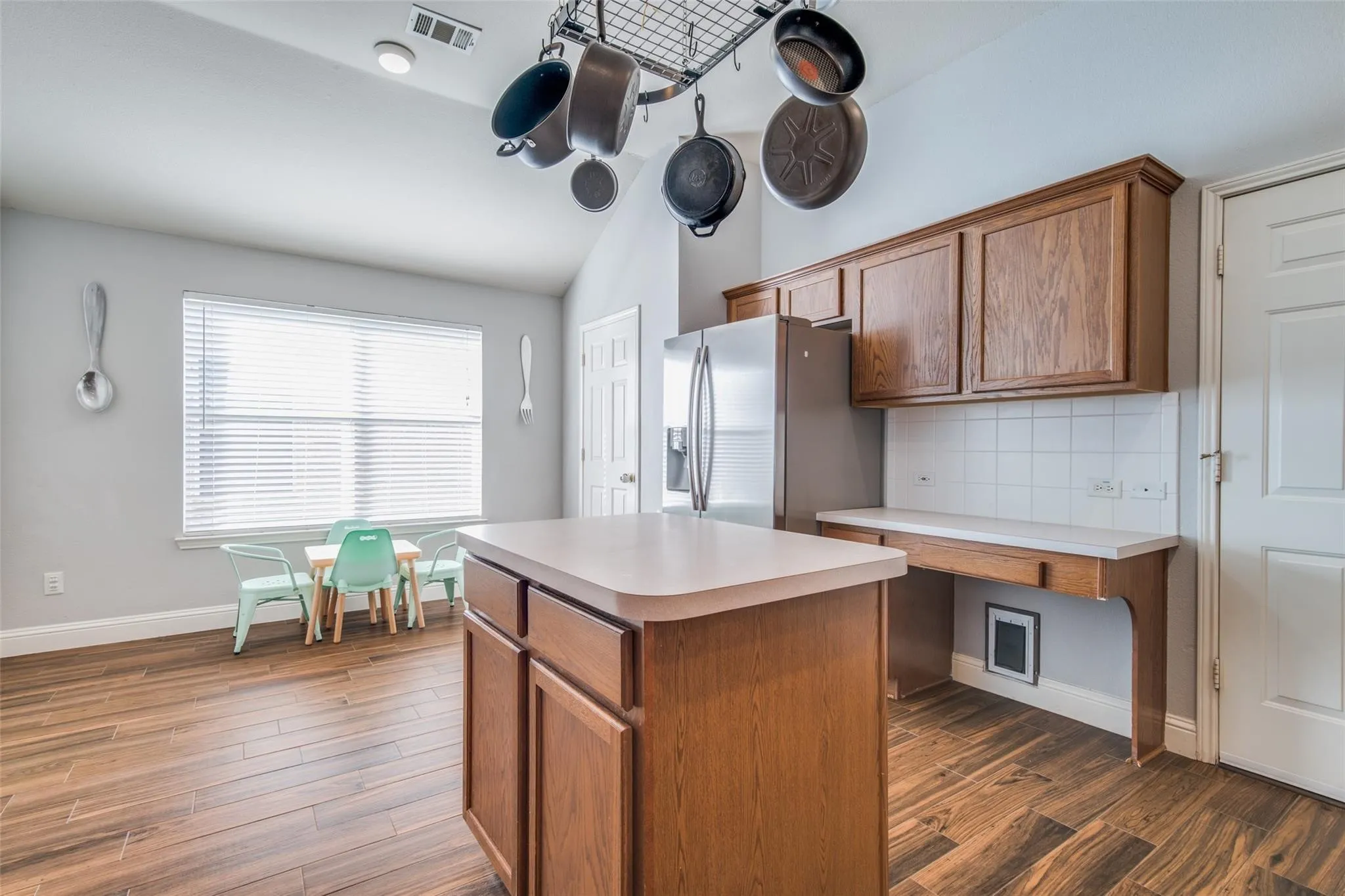 Kitchen featuring an island with countertop, wood-finish flooring, vaulted ceiling, and built-in desk area