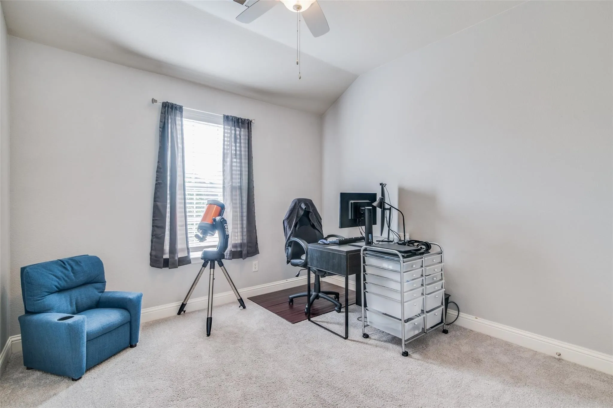 Carpeted room featuring a window with blinds, a ceiling fan, and painted walls