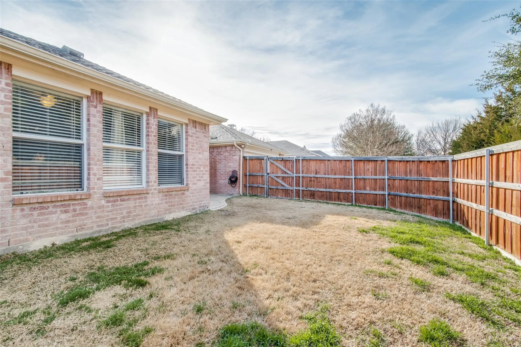 Private backyard featuring a stained wood fence, a large grass area, and a curved concrete pathway