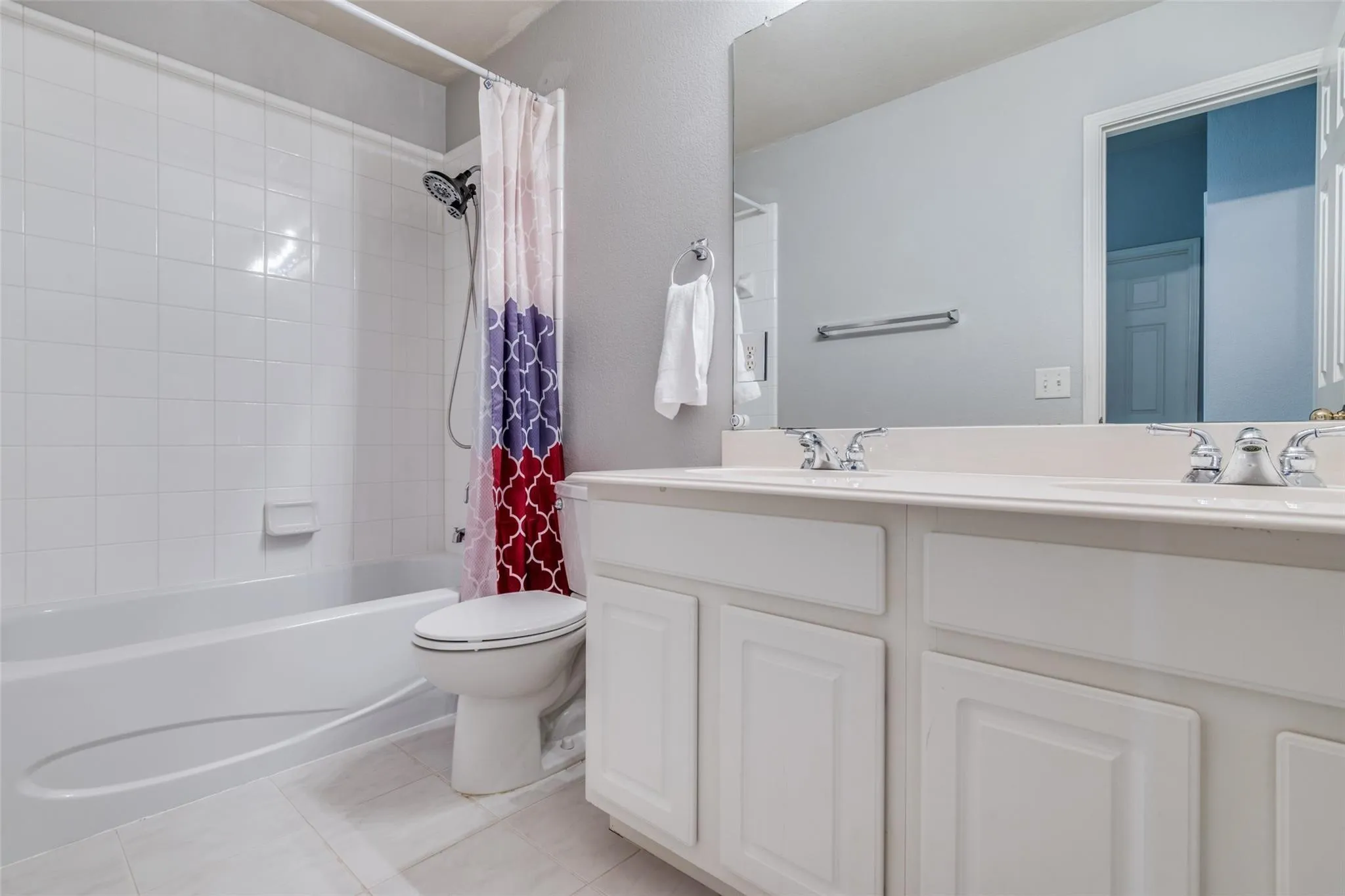 Bathroom featuring a dual vanity with white cabinetry, white countertops, and chrome fixtures