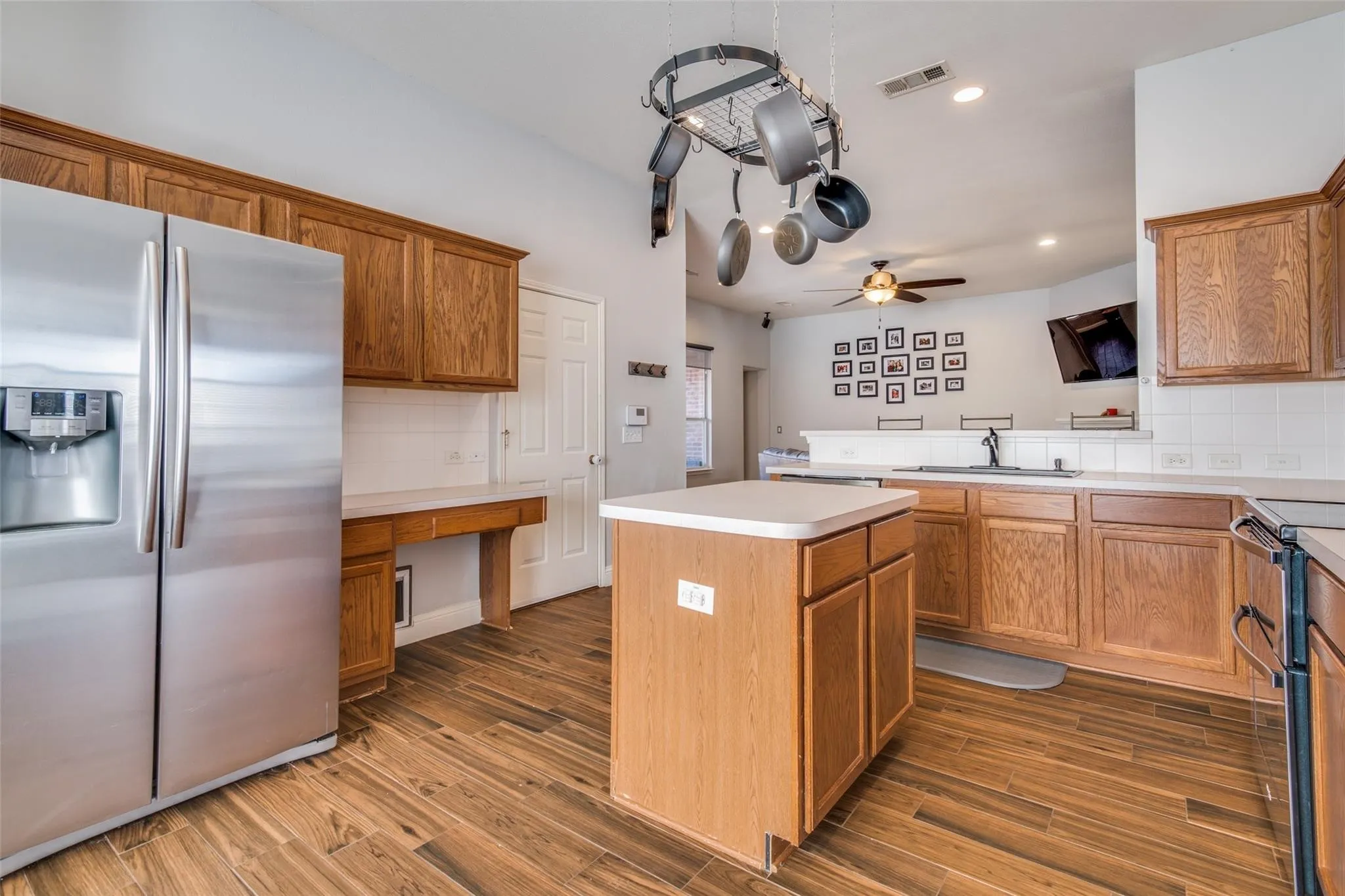 Spacious kitchen featuring wood-finish flooring, wood cabinetry, a central island, and white countertops