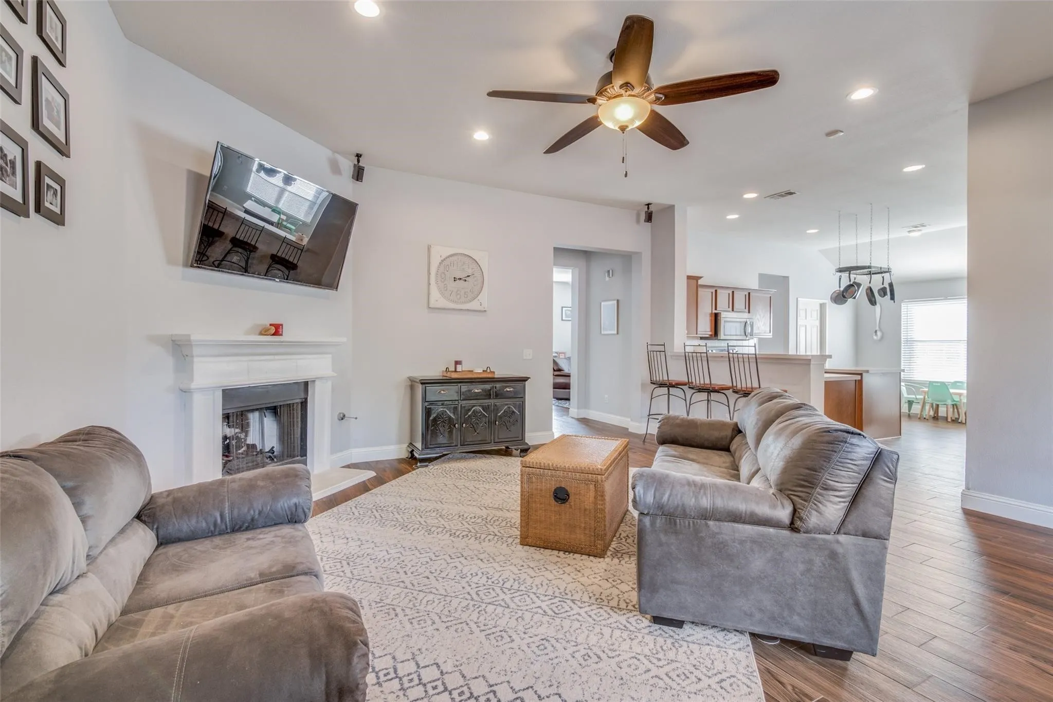 Living room featuring a fireplace with a white mantel, recessed lighting, and a ceiling fan