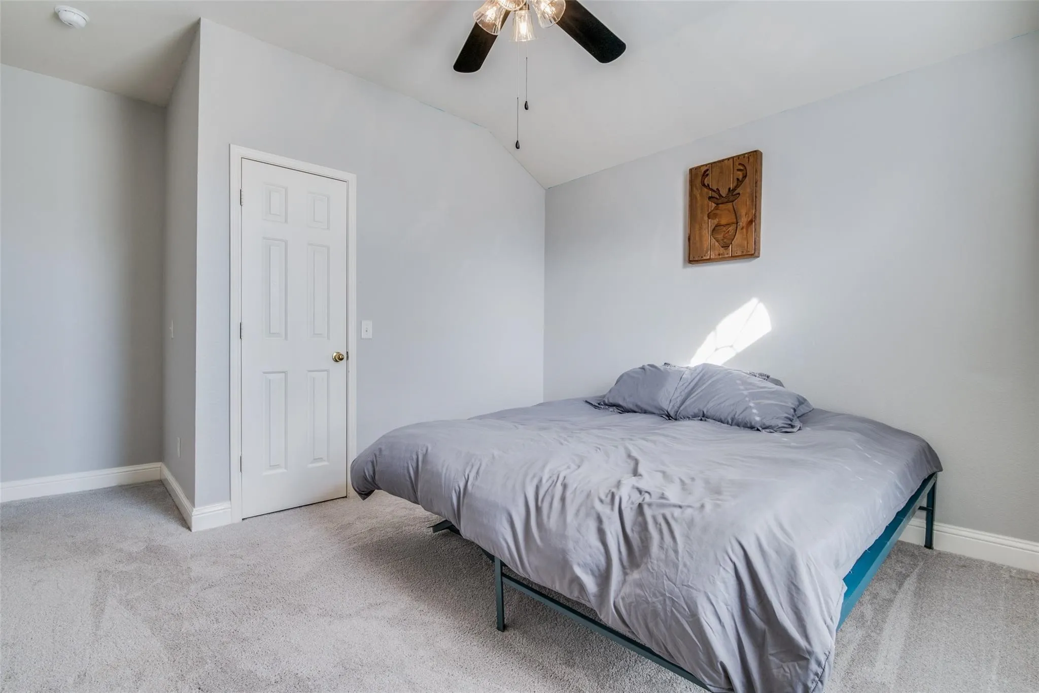 Carpeted room featuring a white paneled door, baseboard molding, a ceiling fan with integrated lighting, and neutral wall tones