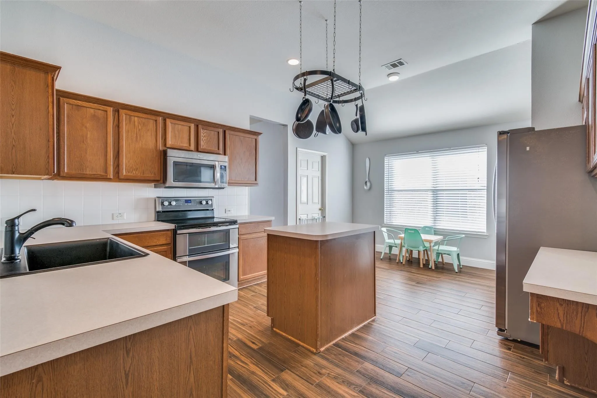 Kitchen featuring wood-finish flooring, wood cabinetry, light countertops, and a white subway tile backsplash