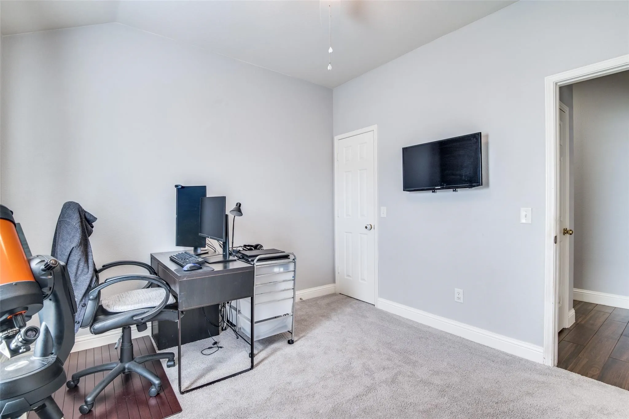 Carpeted room featuring light gray wall paint, white trim, and a white paneled door