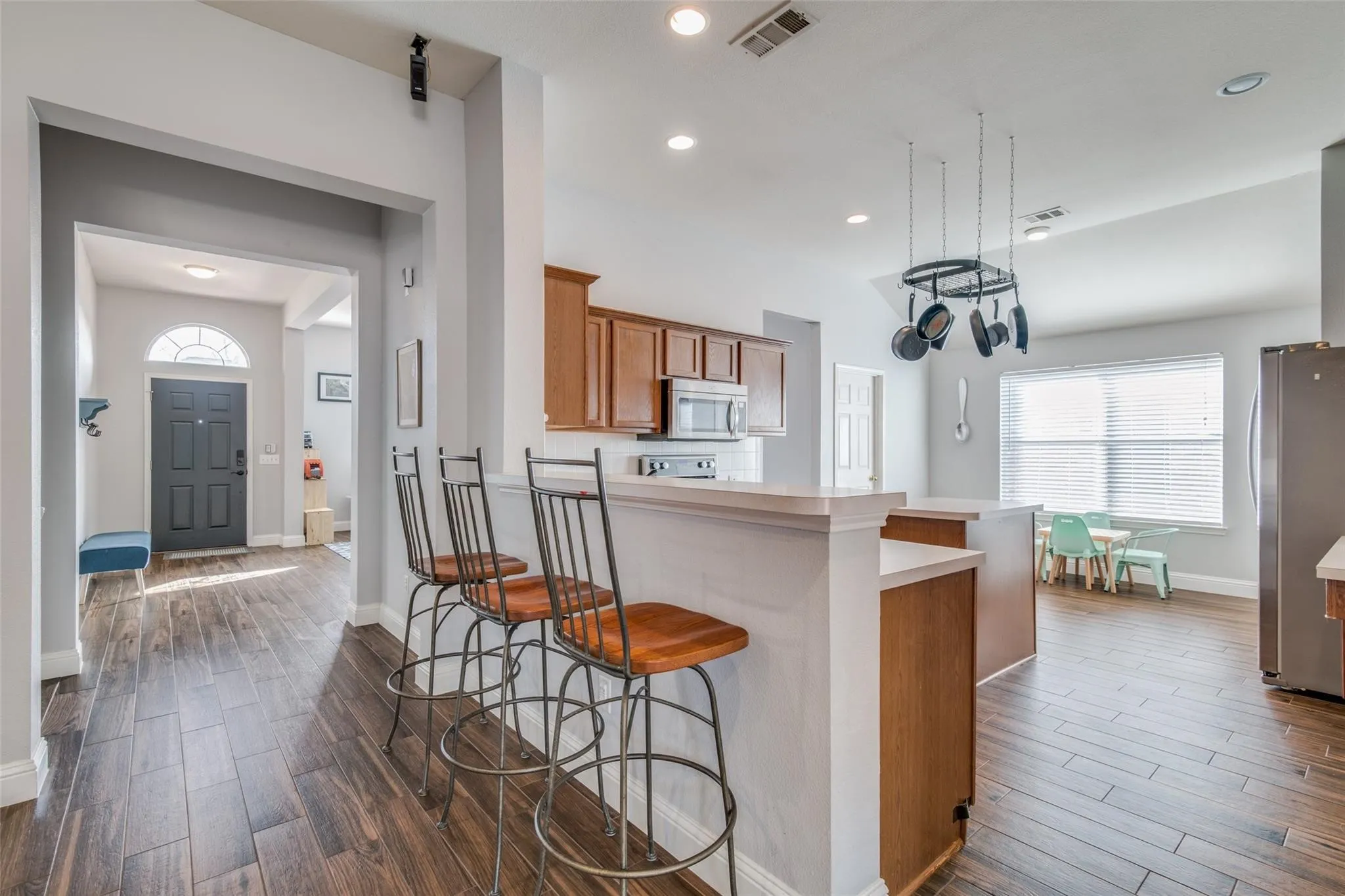 Open-concept kitchen featuring wood-finish flooring, recessed lighting, wood cabinetry, and a breakfast bar