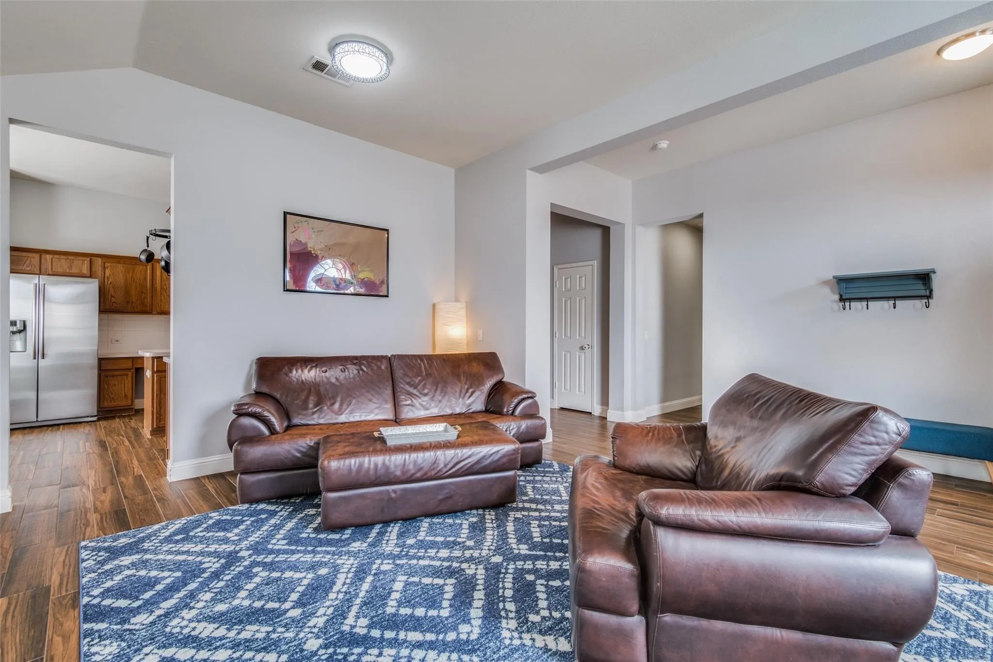 Open-concept living space featuring wood-finish flooring, a contemporary ceiling light fixture, and light-toned walls