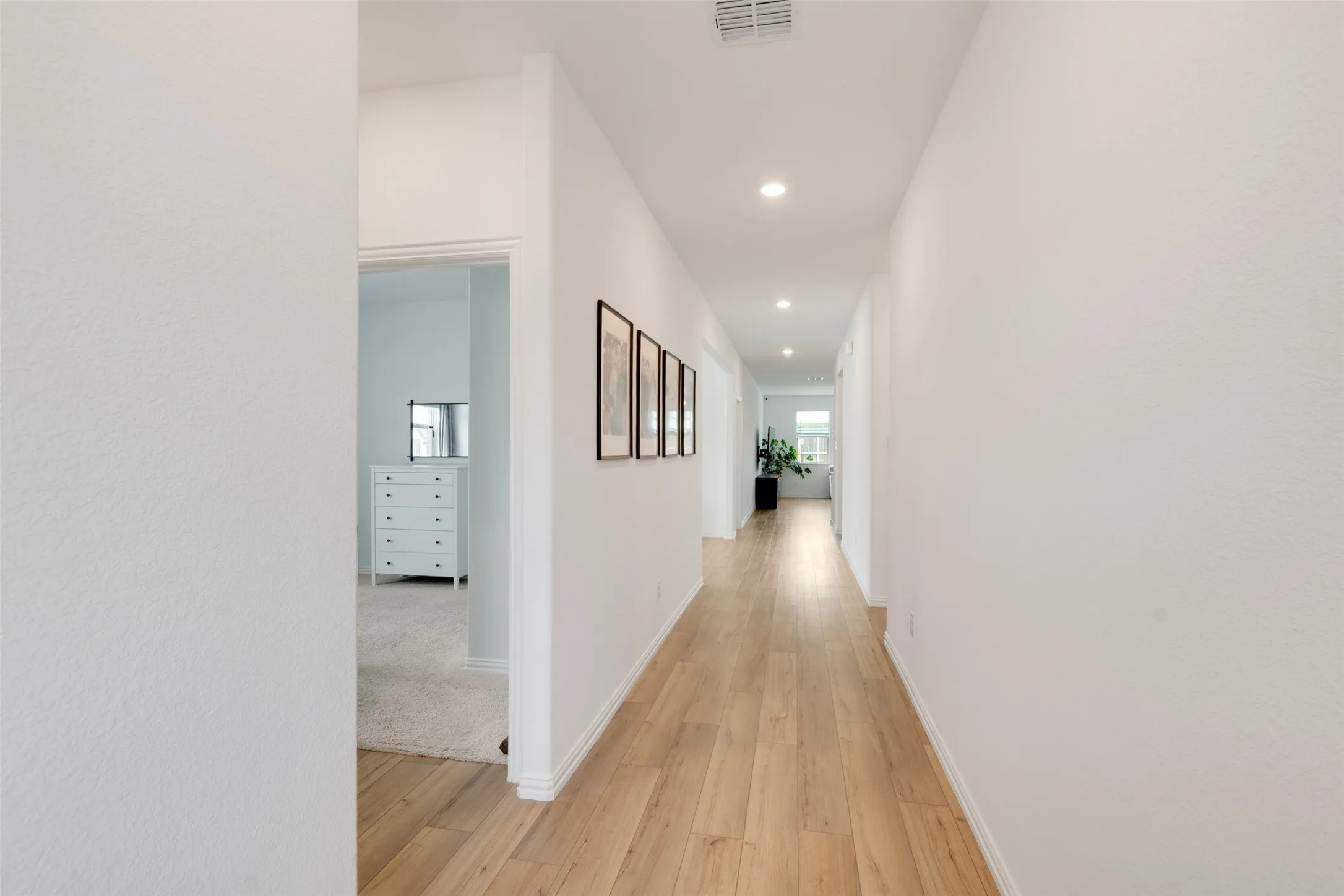 Hallway with LVP flooring, recessed lighting, white walls, and white baseboards