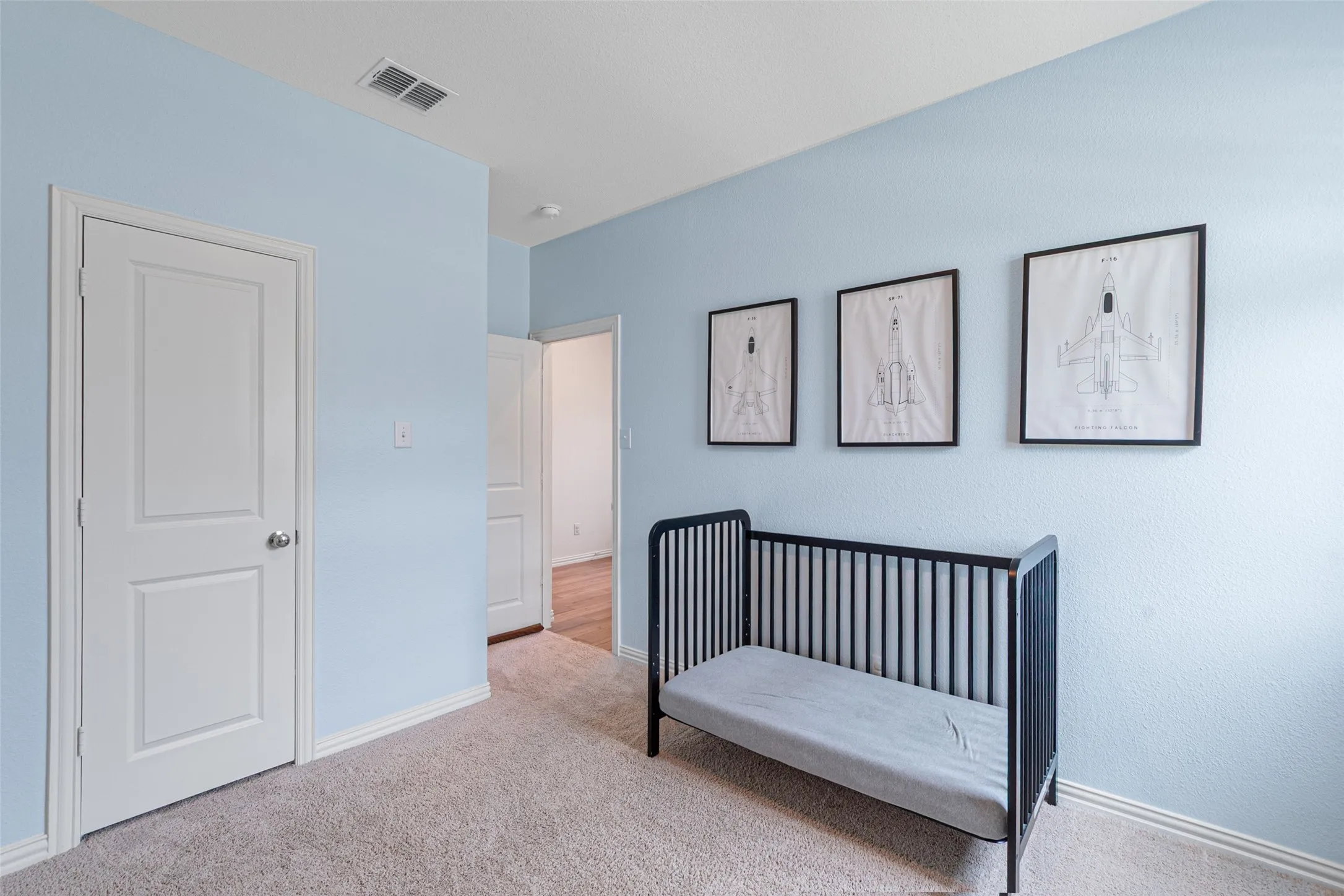 Soft blue painted walls feature white trim and a neutral carpeted floor