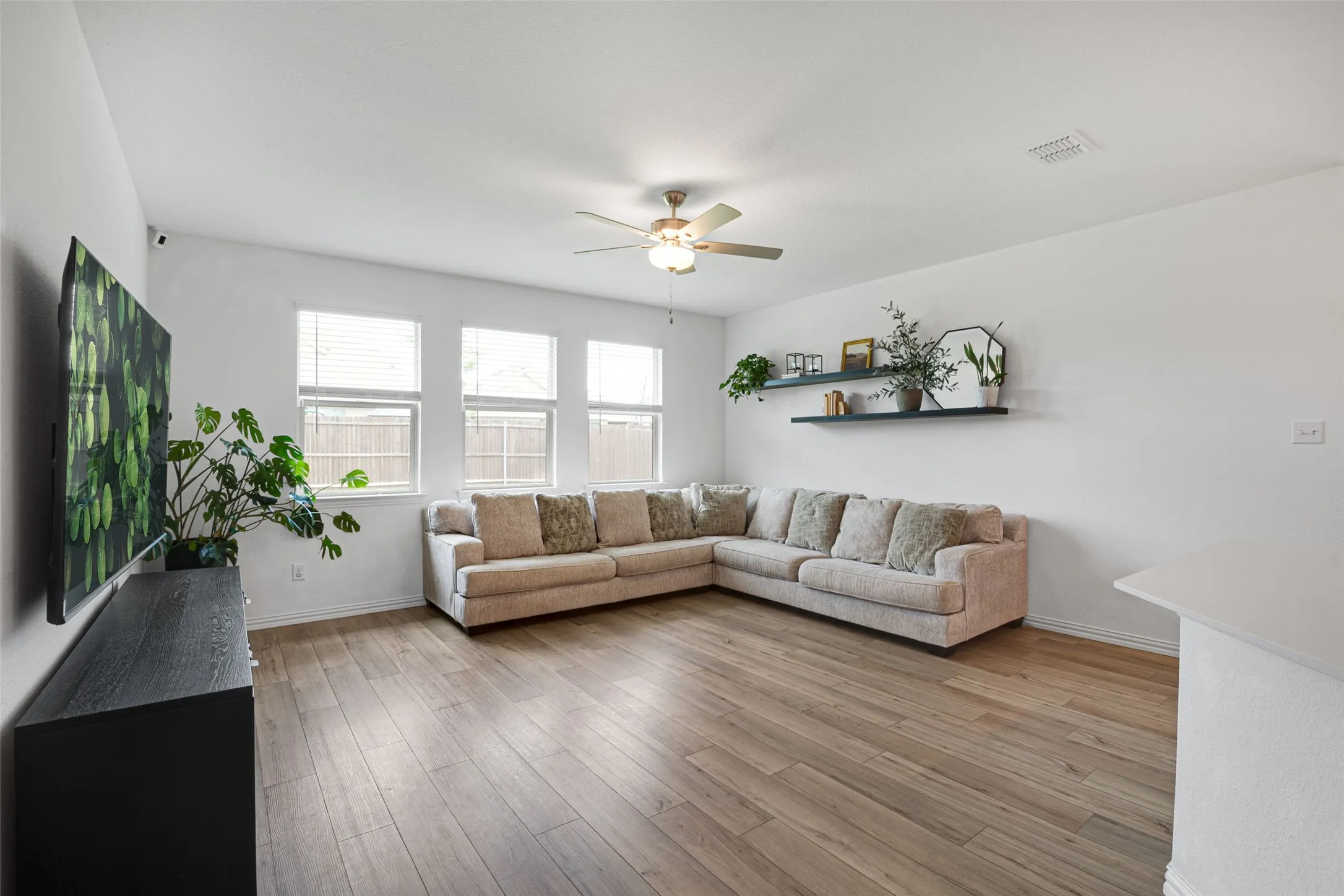 Spacious living area featuring LVP flooring, recessed lighting, and multiple windows with blinds