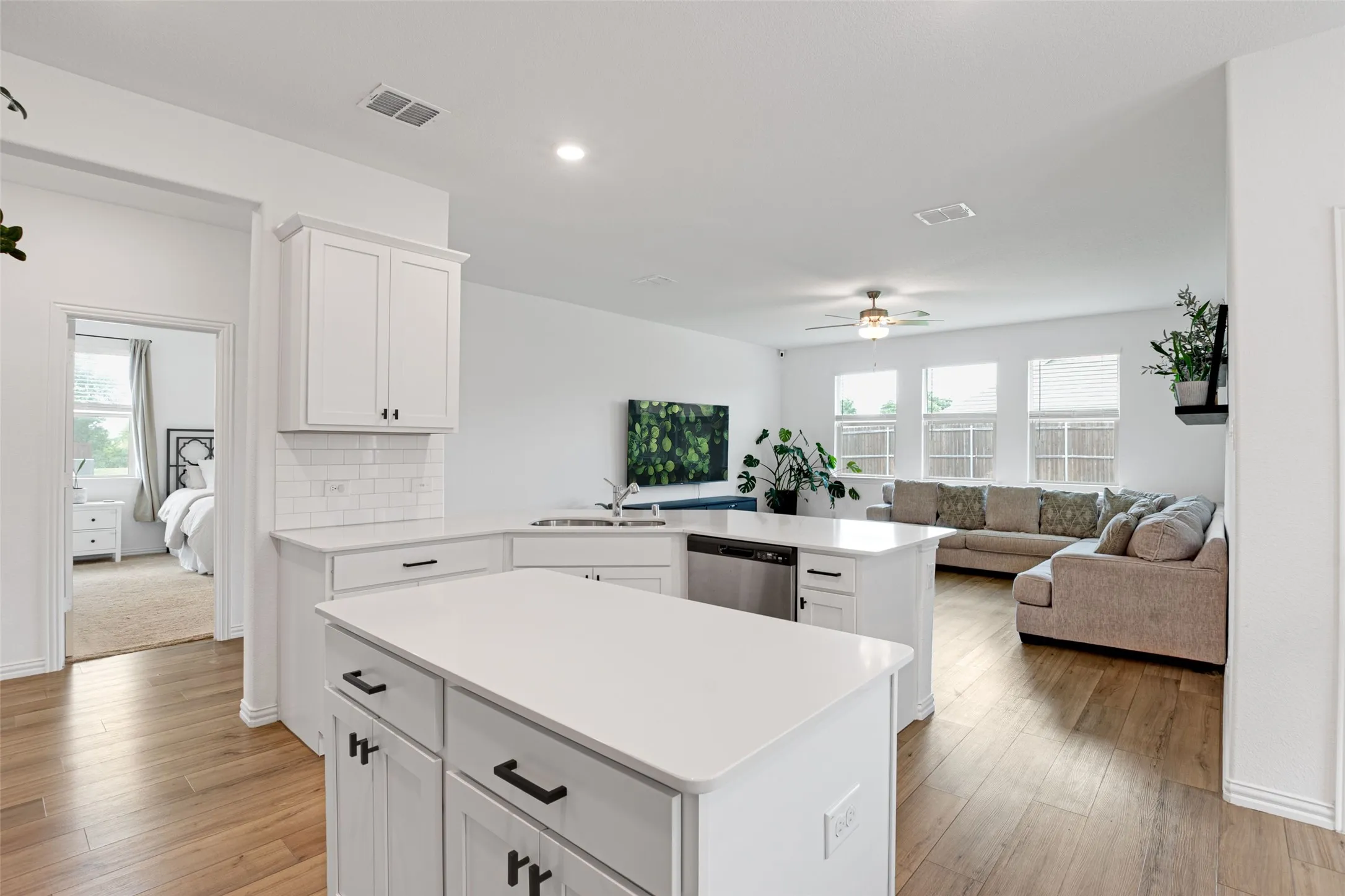 Open-concept kitchen featuring white cabinetry, a white subway tile backsplash, and a central island with a white countertop