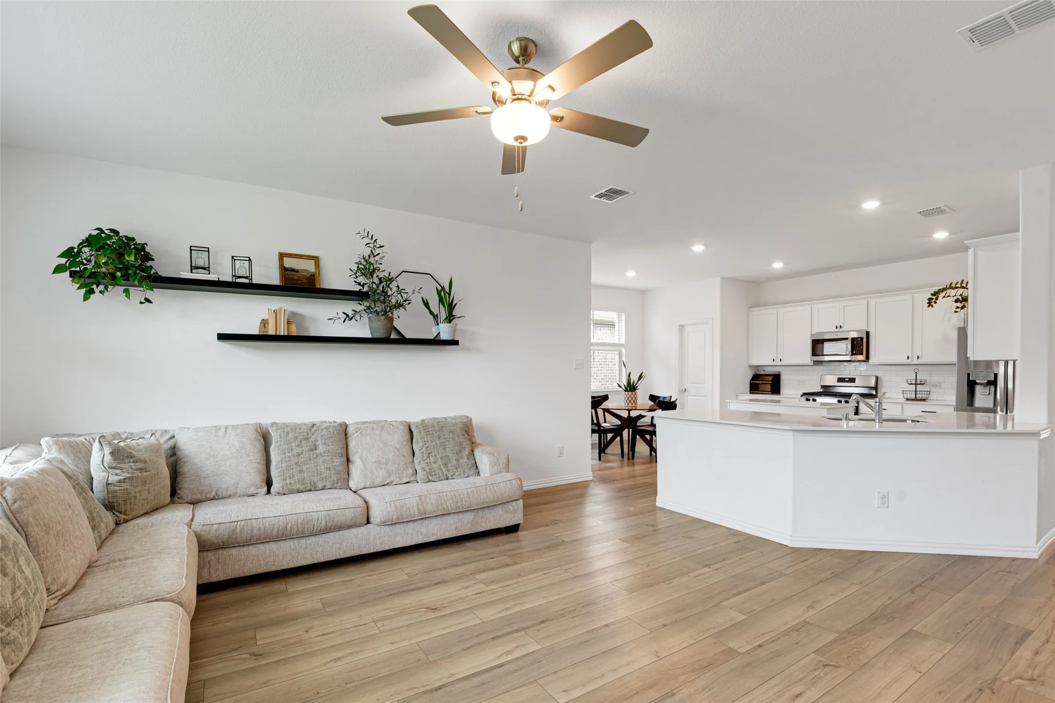 Open-concept living space featuring LVP flooring, recessed lighting, and a ceiling fan