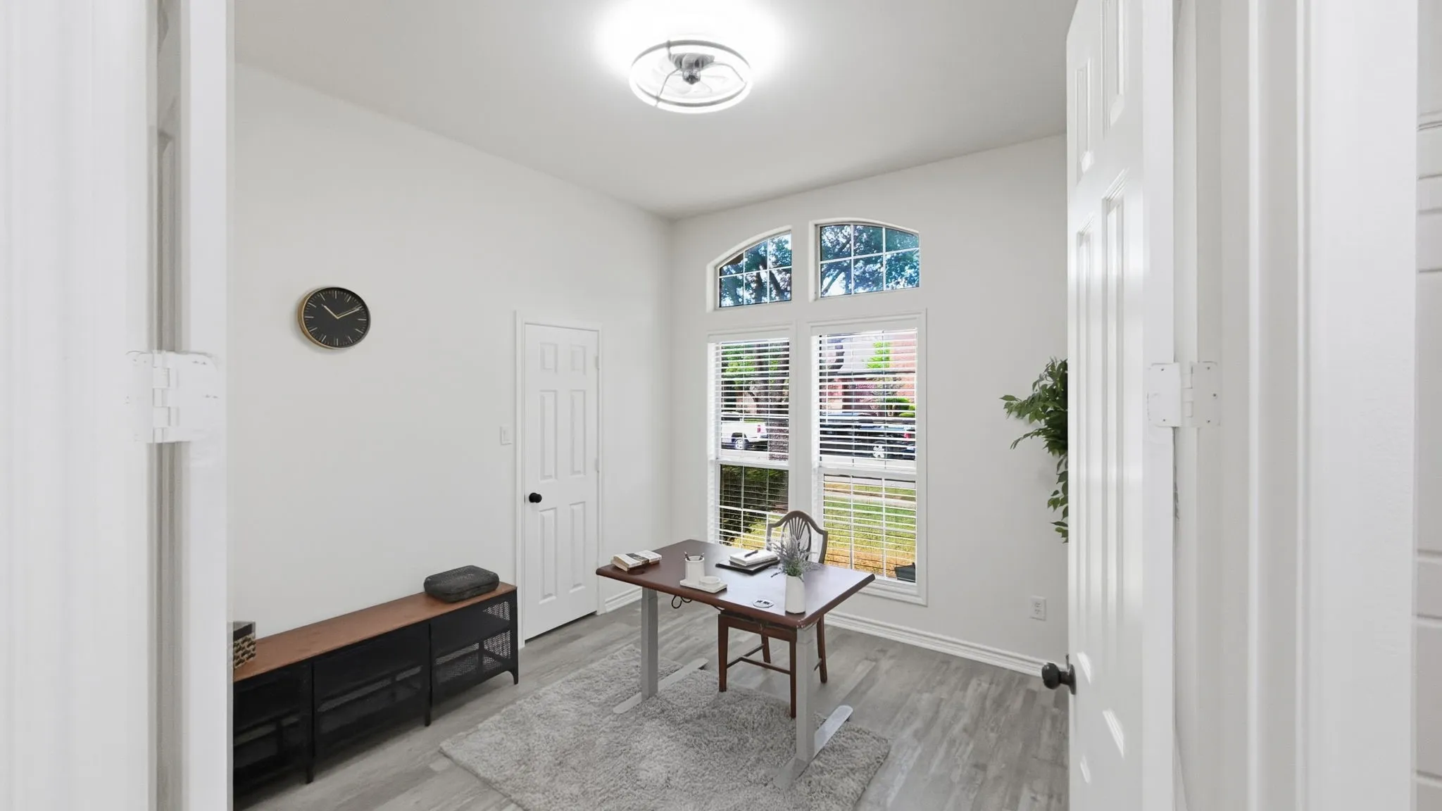 Arch-top window with blinds, wood-finish flooring, recessed lighting, and a paneled door with dark hardware