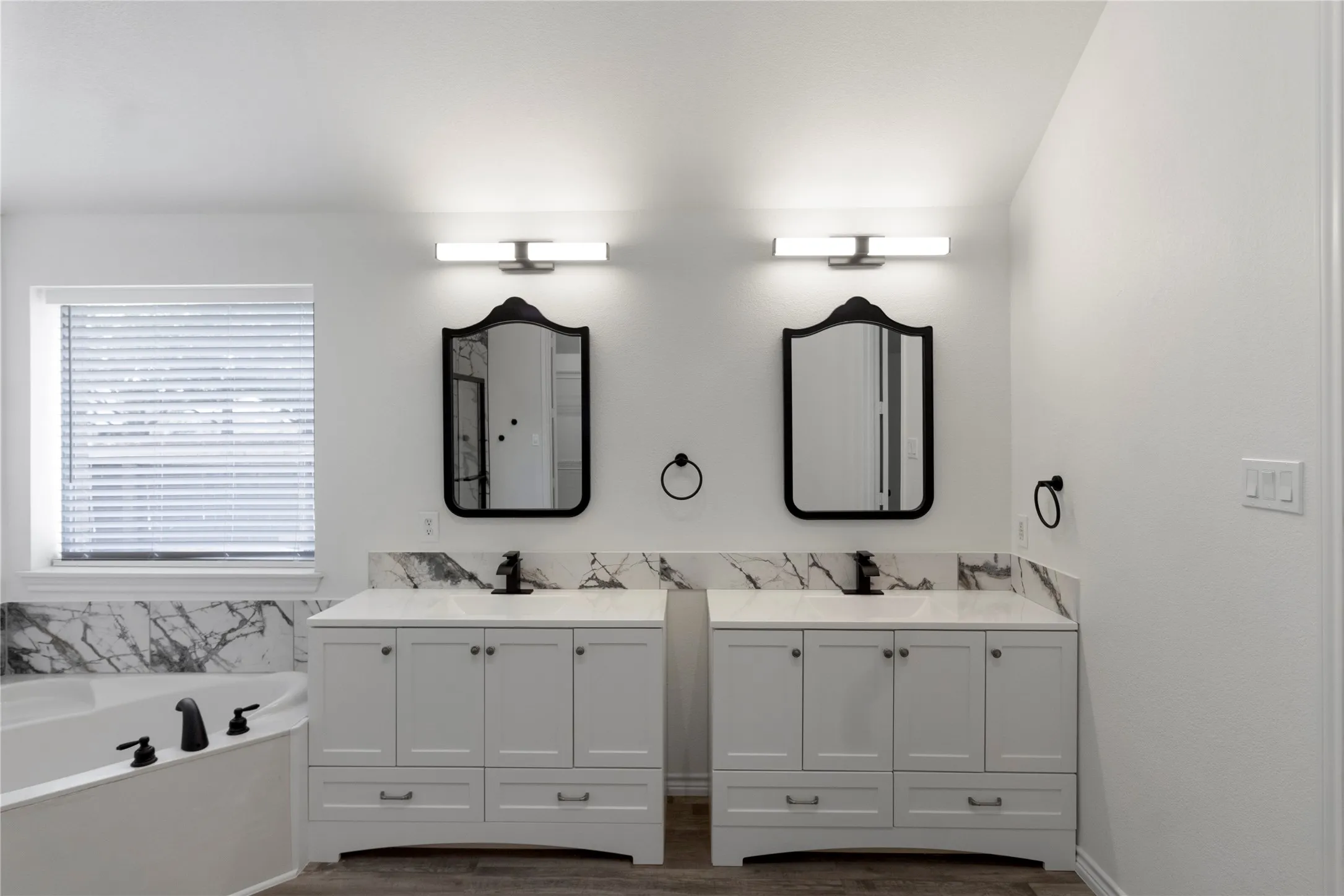 Dual white vanity cabinets with integrated sinks and black fixtures, featuring white countertops with dramatic black veining