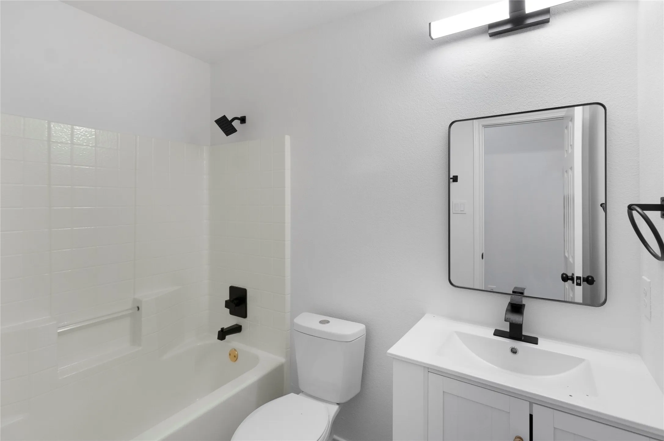 Contemporary bathroom featuring a white vanity with integrated sink, rectangular framed mirror, and a modern light fixture